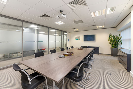 Modern conference room with glass walls, ideal for meetings and presentations.
