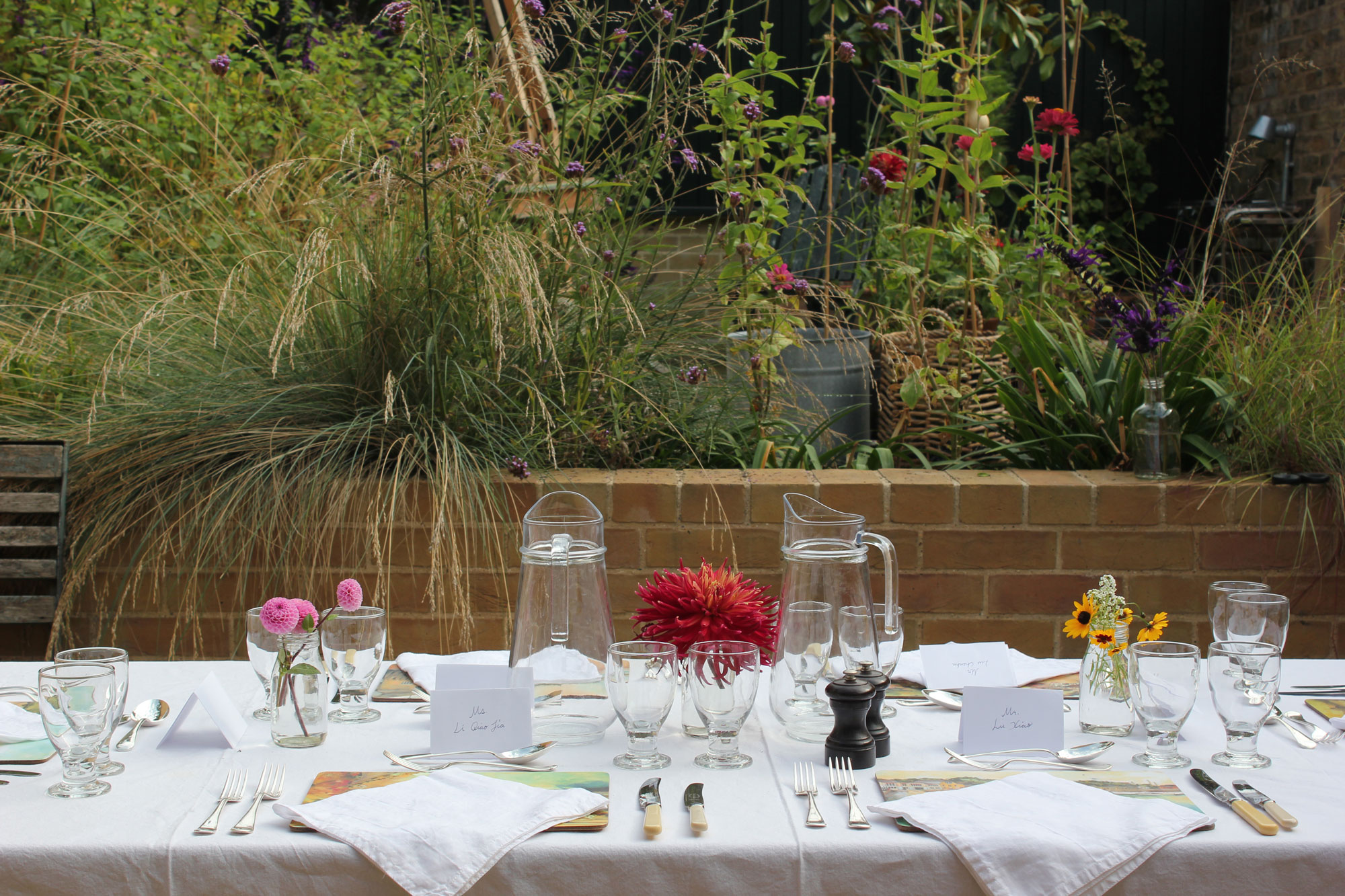 Outdoor dining table with floral centerpieces at Van Gogh House garden event.