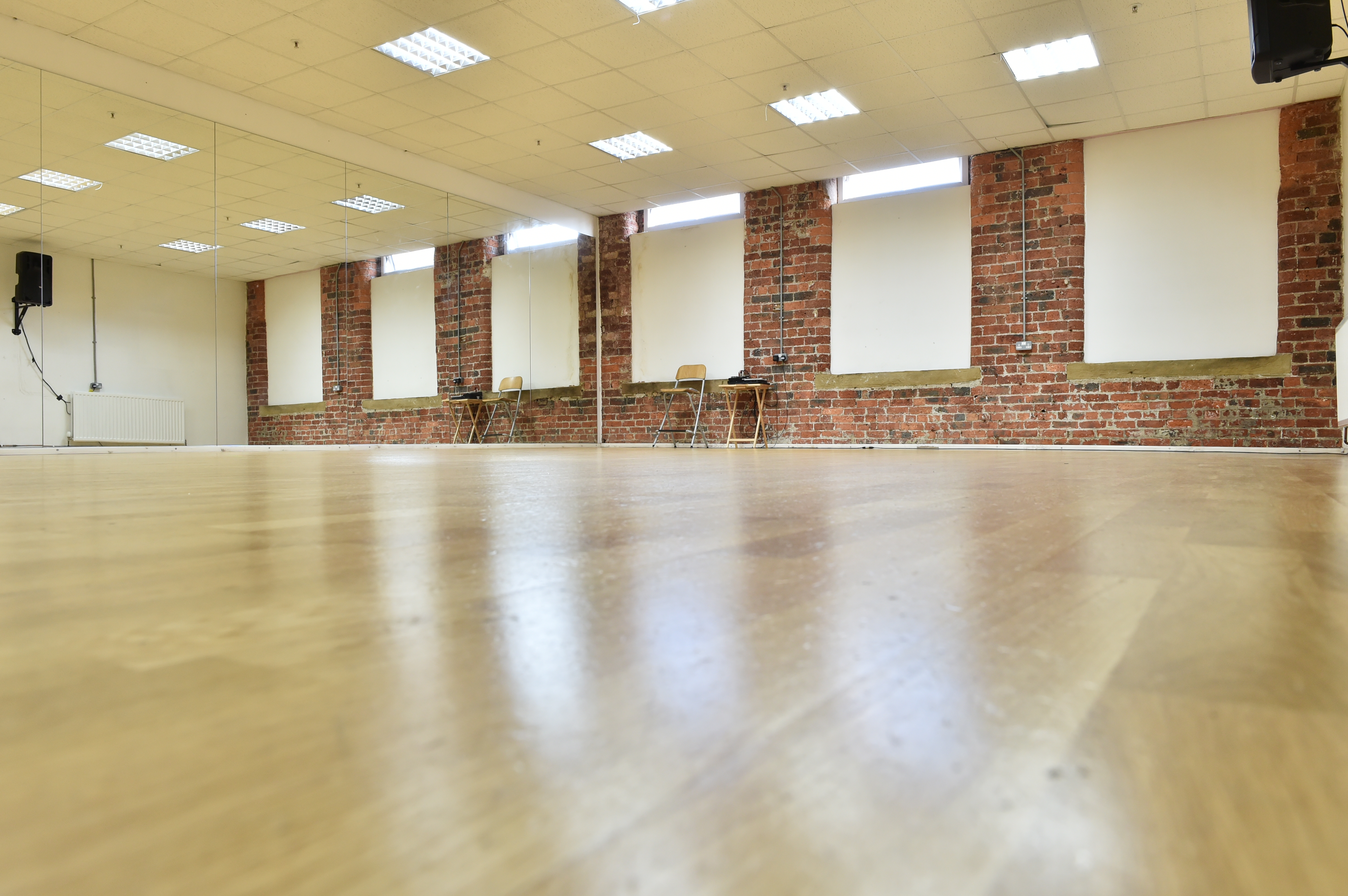 Spacious dance studio with wooden floors, ideal for workshops and fitness events.