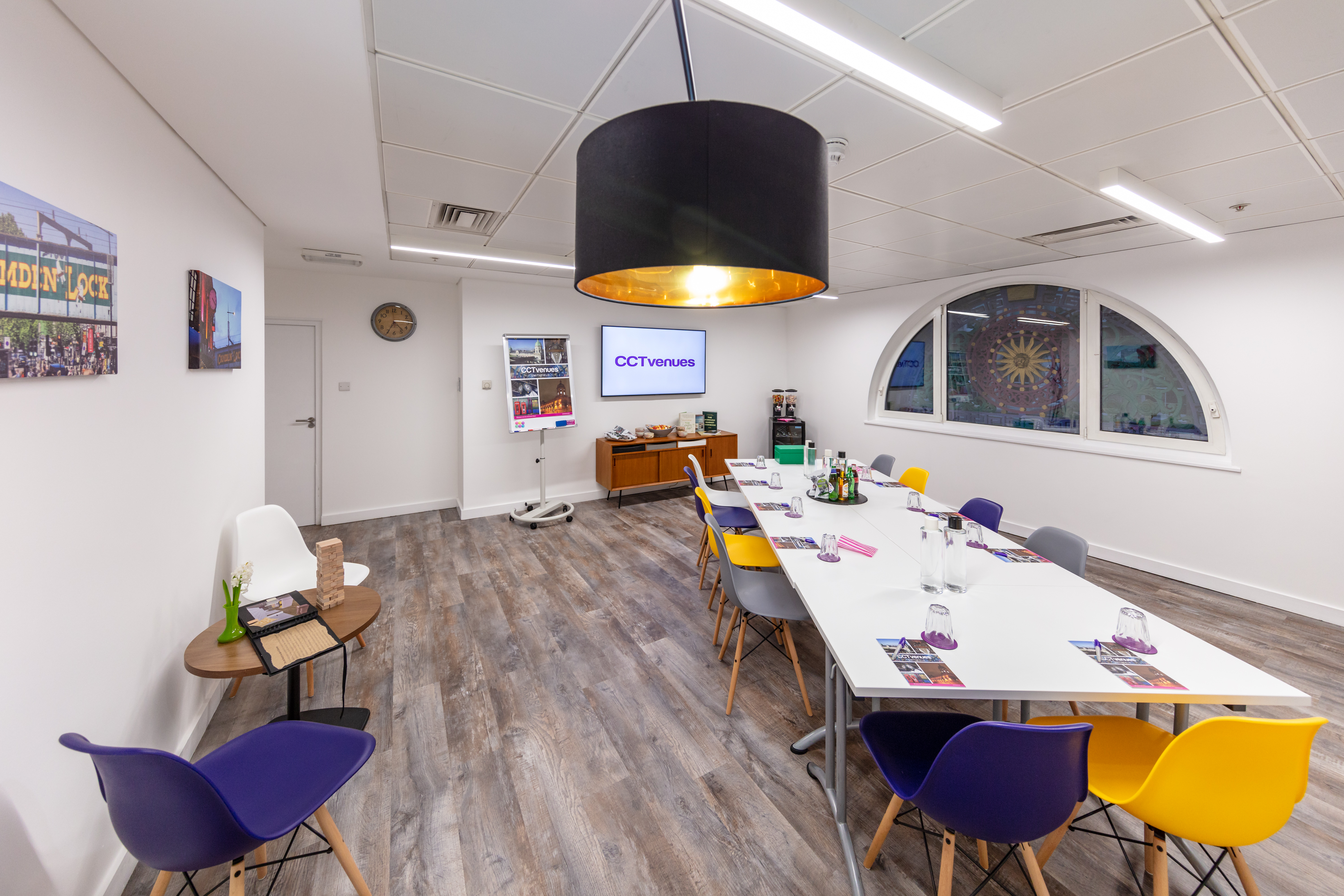 Modern meeting room at Camden Lock, featuring a long table and colorful chairs for collaboration.
