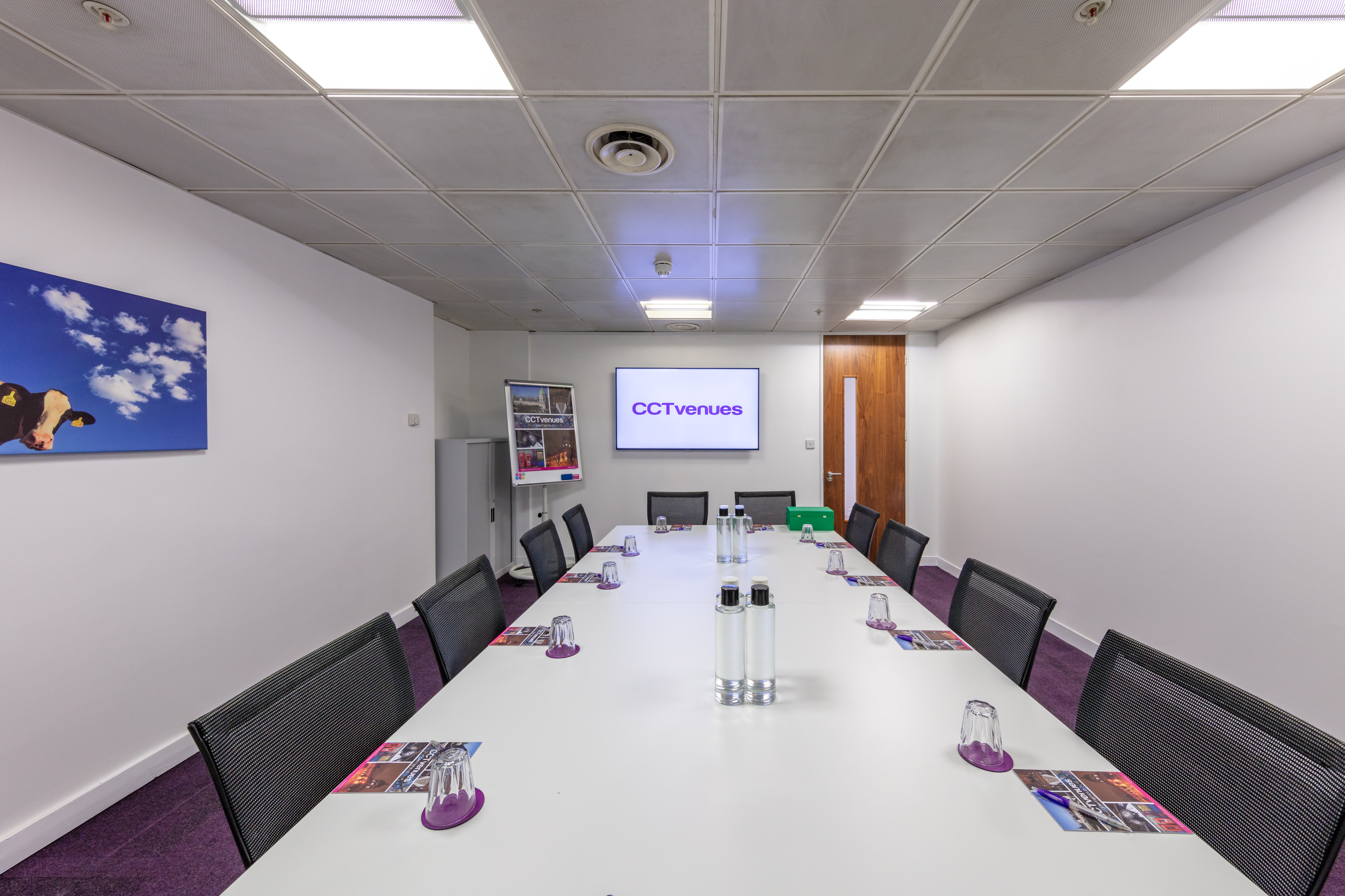Modern meeting room with long table and purple accents for professional gatherings.