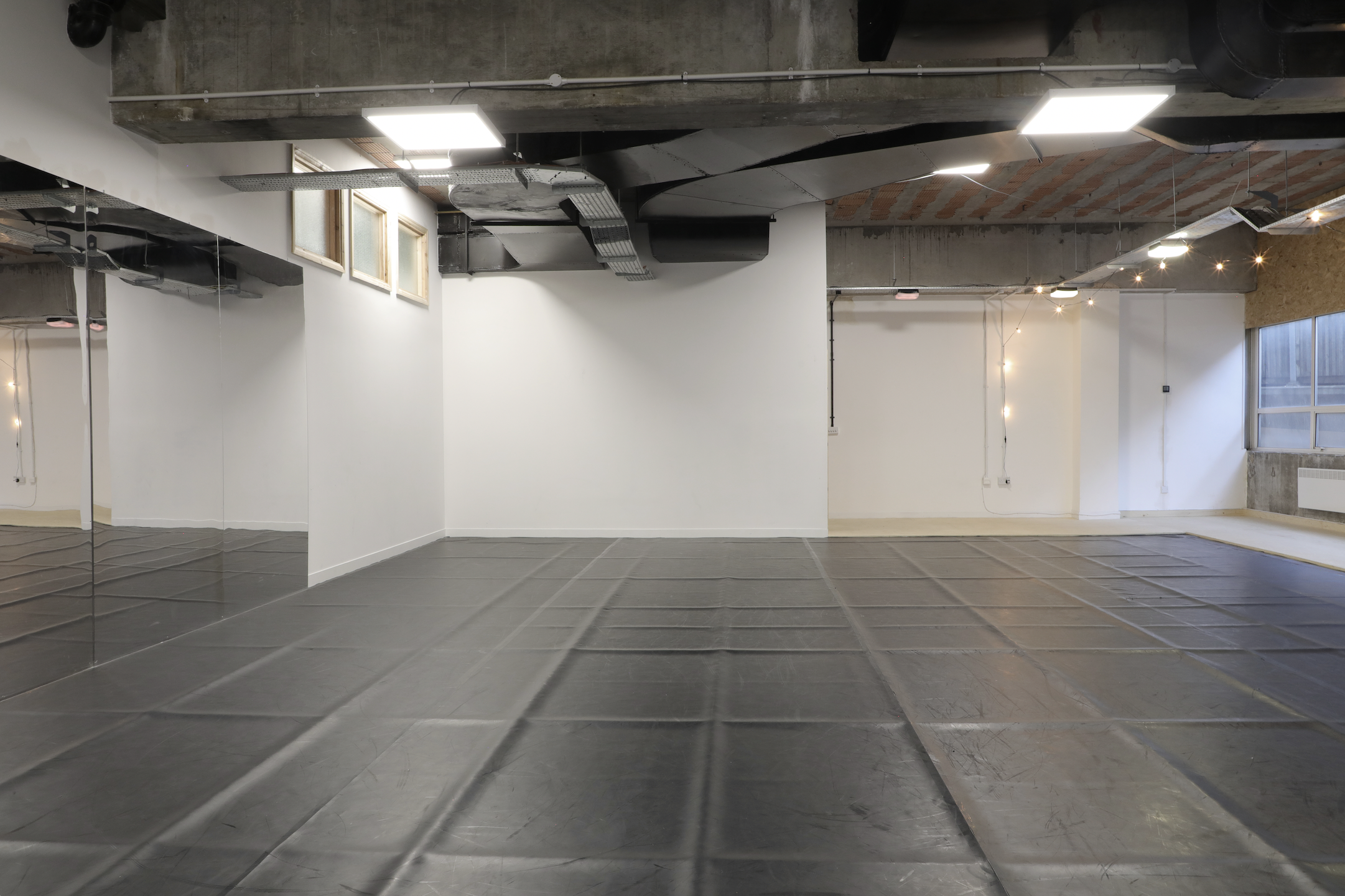 Dance studio with polished black flooring, ideal for workshops and yoga classes.