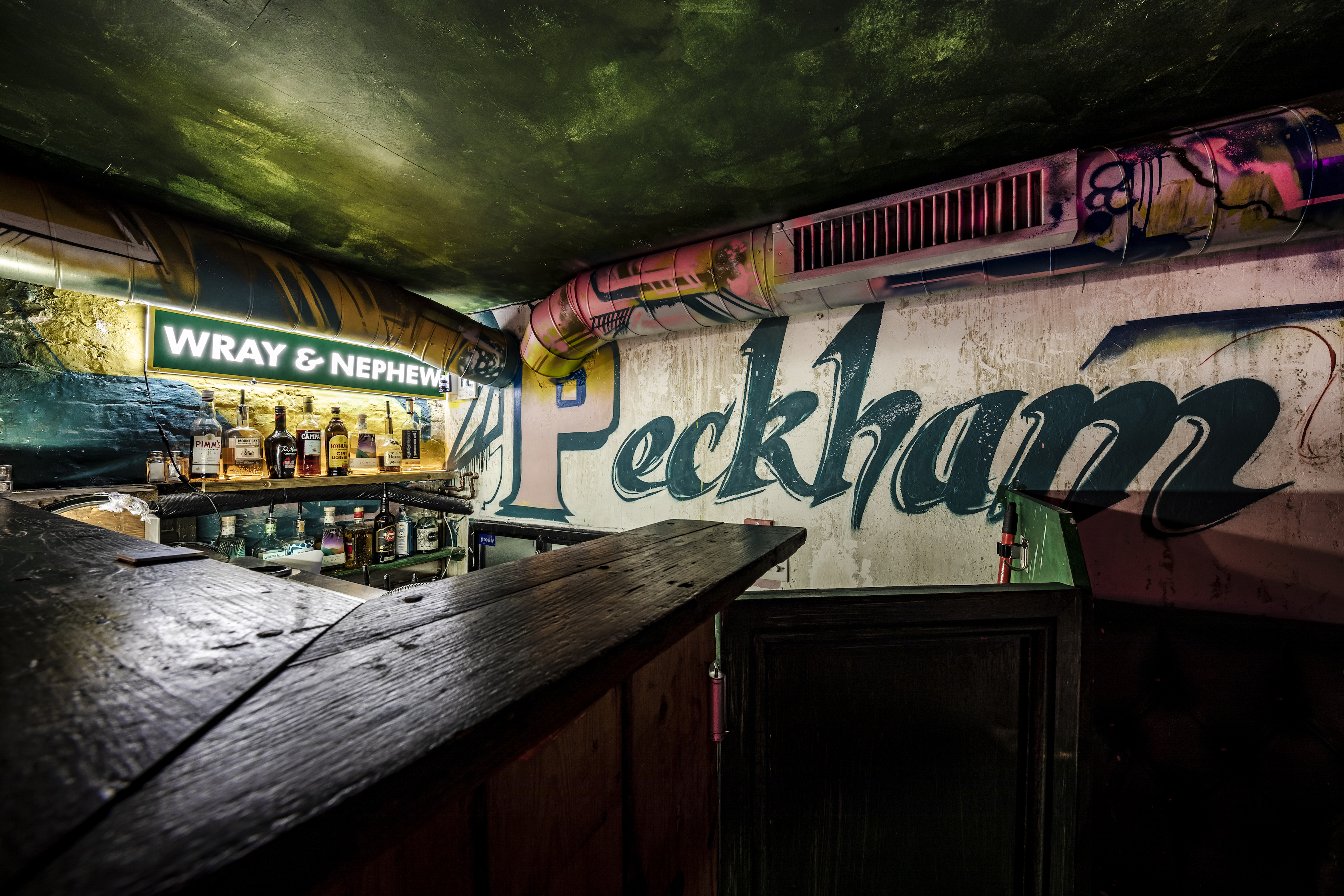 Vibrant urban bar with graffiti mural, perfect for casual gatherings and events.