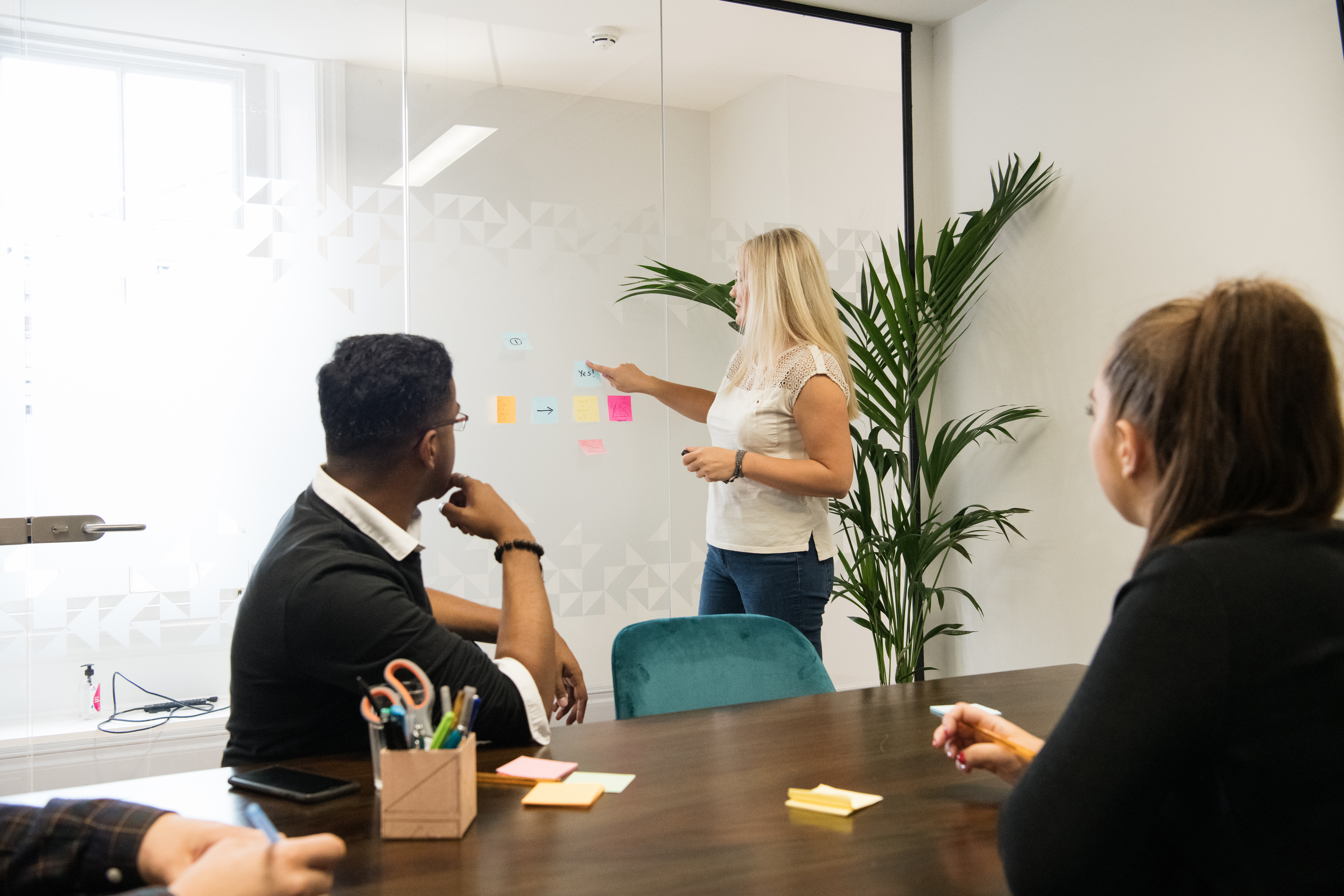 "Collaborative meeting in 1899 Suite, Wizu Workspace with glass board and sticky notes."