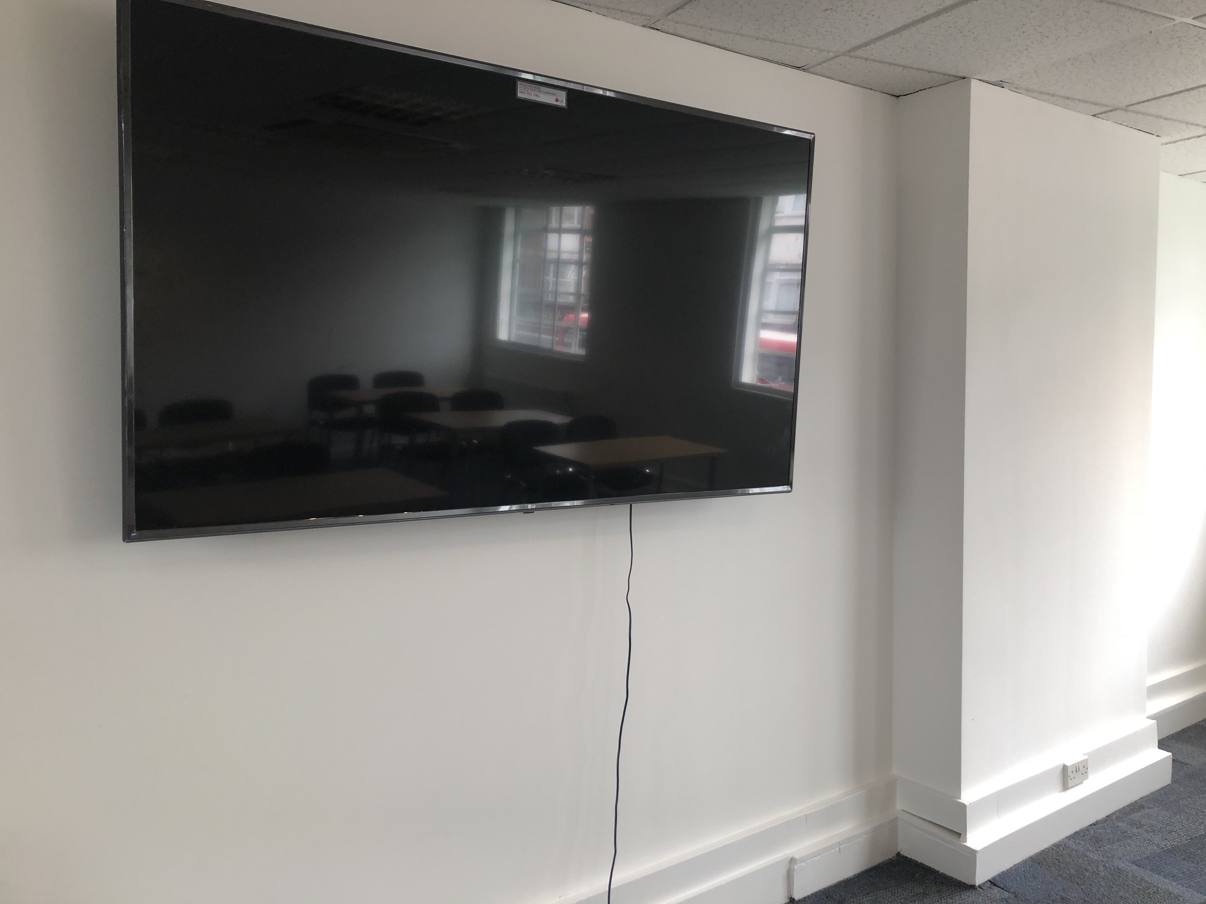 Minimalist seminar room with wall-mounted TV, ideal for presentations and meetings.