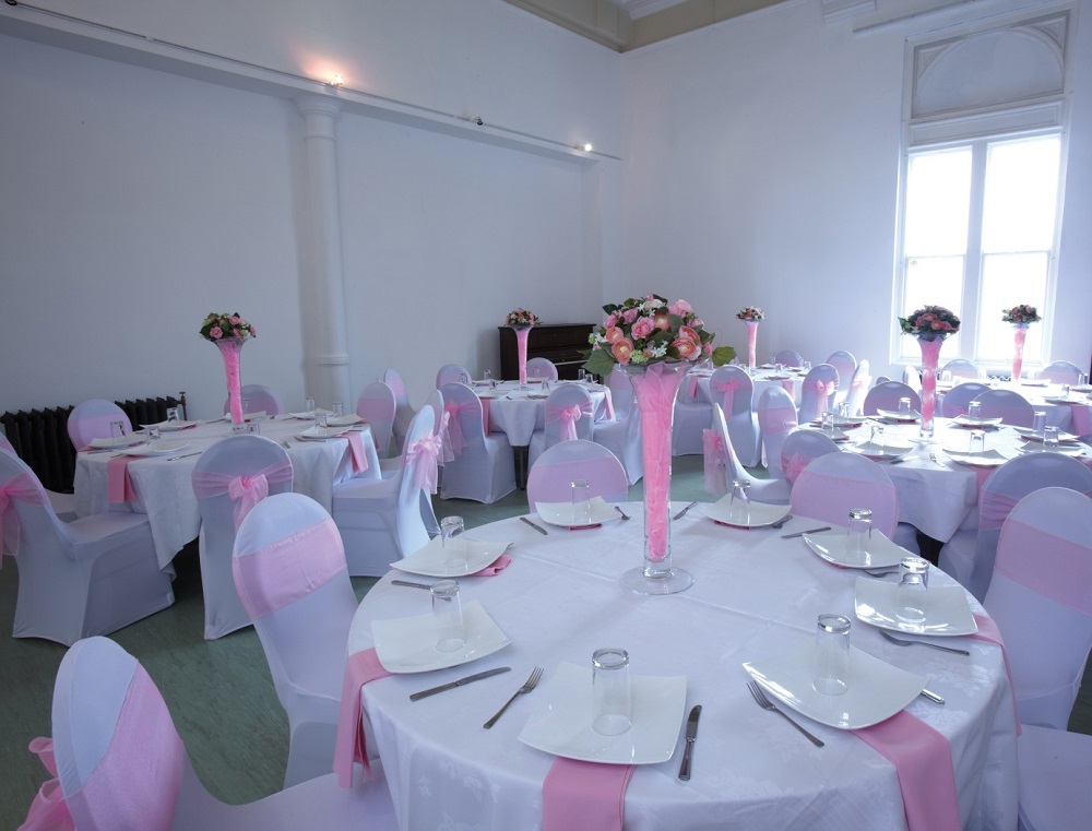Indus Hall at Kala Sangam: elegant wedding venue with pink-accented tables and floral centerpieces.