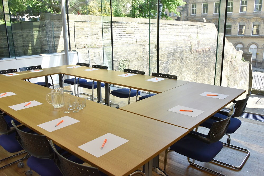 Glass meeting room with U-shaped table, perfect for collaborative business events.