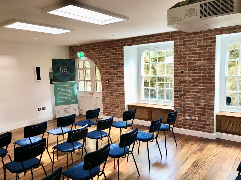 Abraham Room: modern meeting space with exposed brick, ideal for workshops and events.