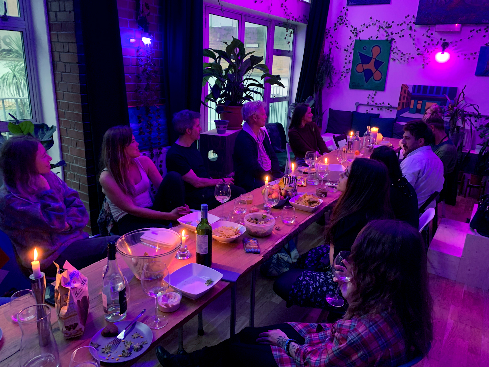 Intimate networking event on Kingsland Road with cozy purple lighting and long table setup.