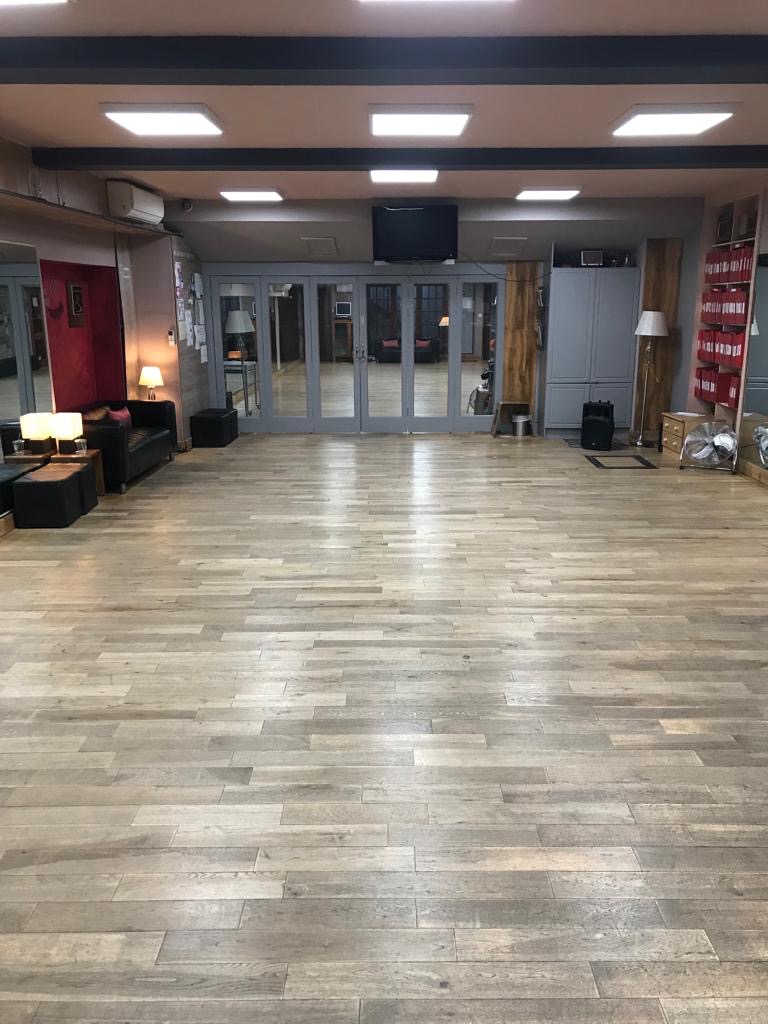 Spacious event venue with polished wooden floors, ideal for workshops and receptions.