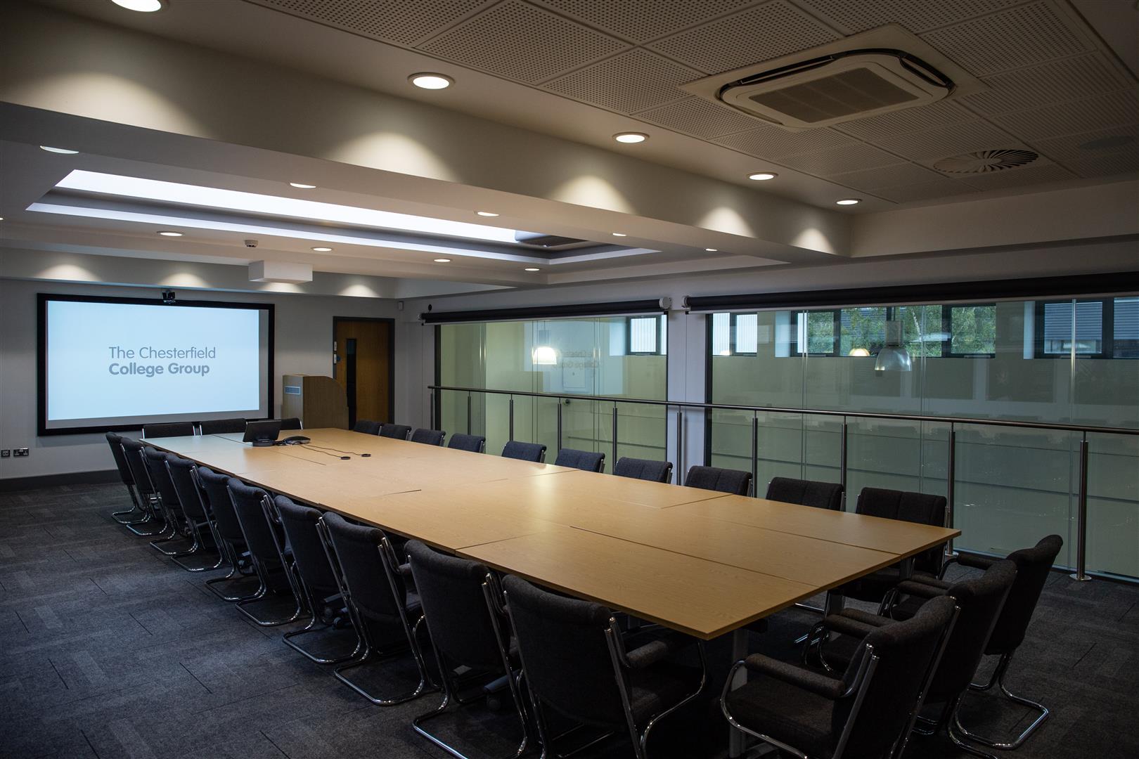 Modern conference room at Chesterfield College with long table and projector screen.