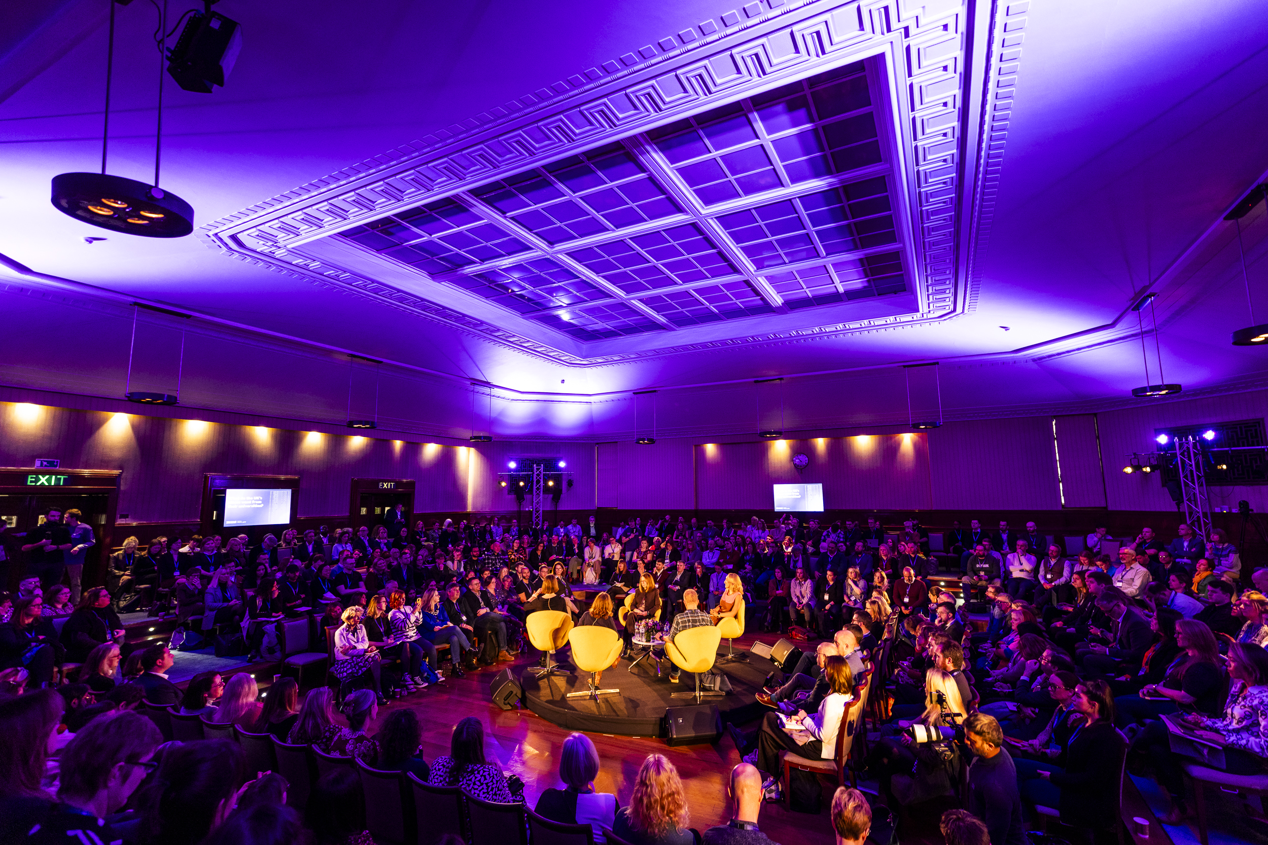 Panel discussion at Beveridge Hall, University of London, with engaged audience and dynamic lighting.