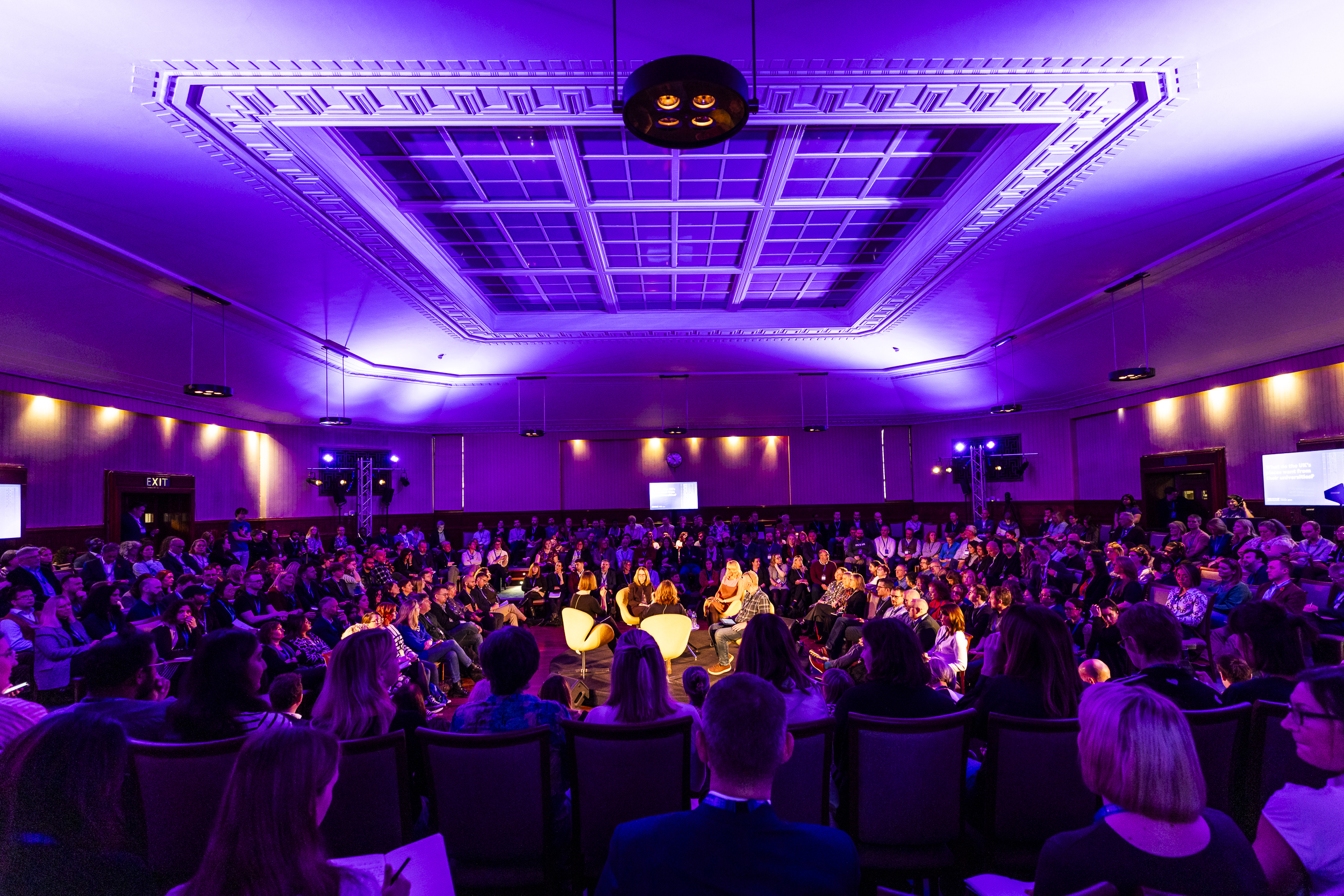 Panel discussion in Beveridge Hall, University of London, with circular seating and ambient lighting.