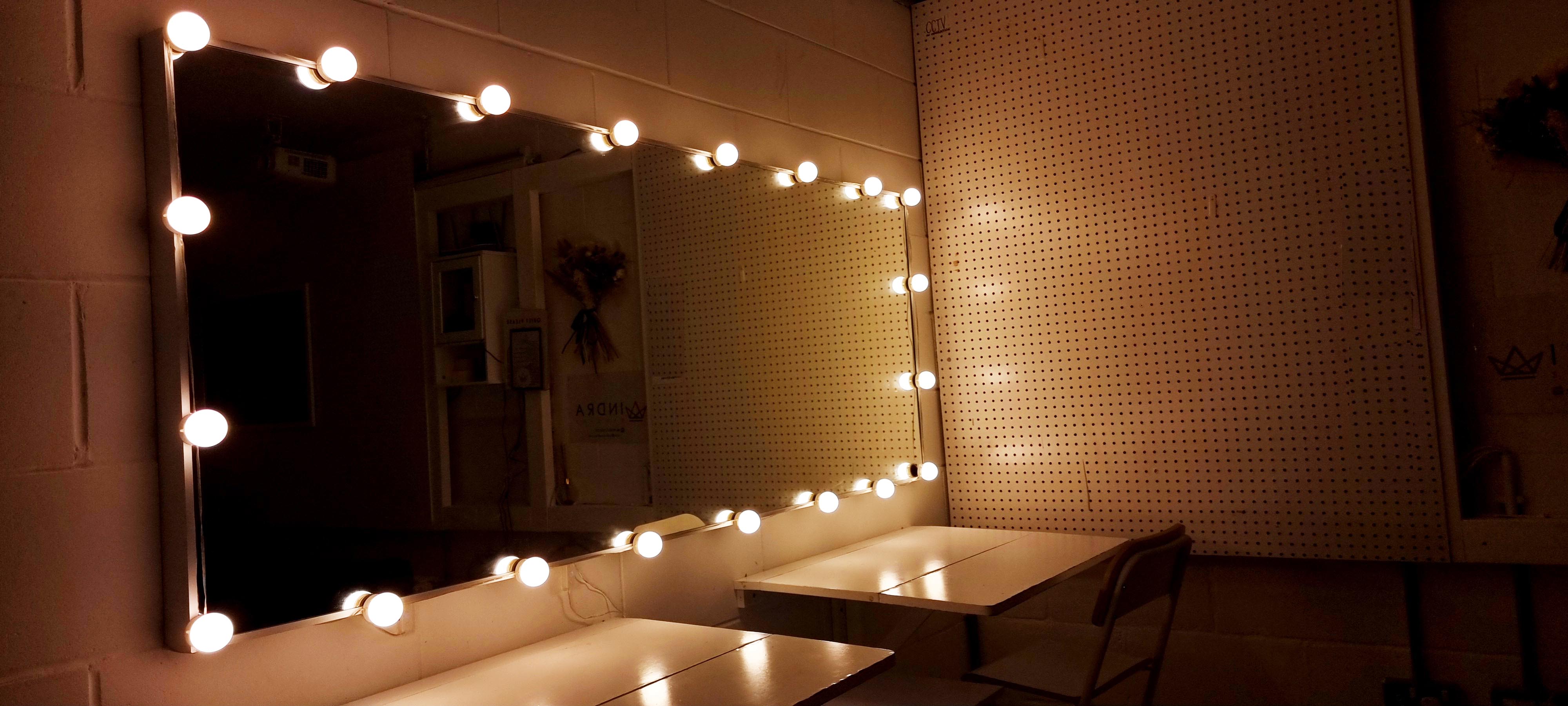 Vanity area with bright bulbs in Infinity Cove studio for event preparations.
