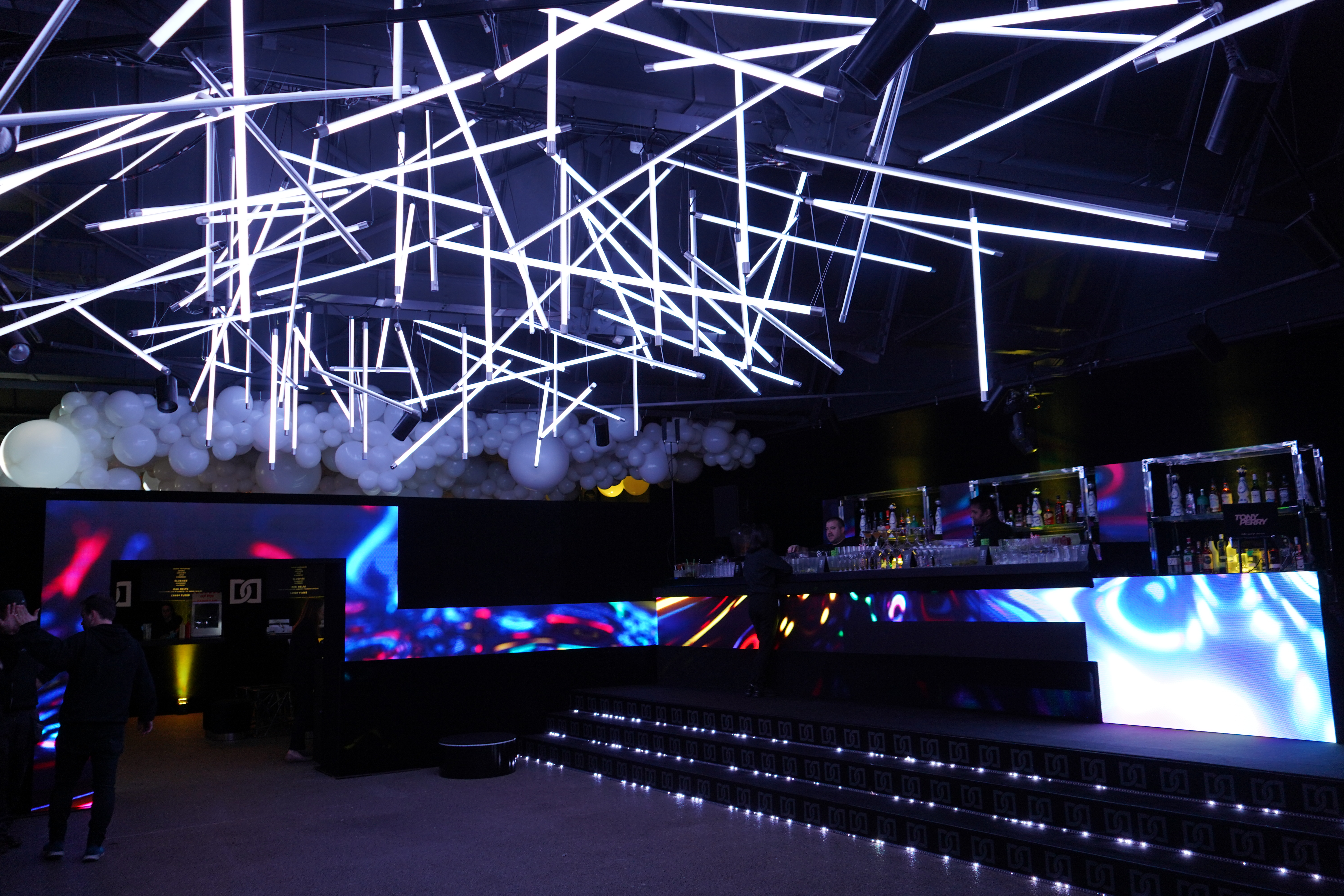 Modern event space with dynamic lighting and sleek bar, ideal for corporate gatherings.