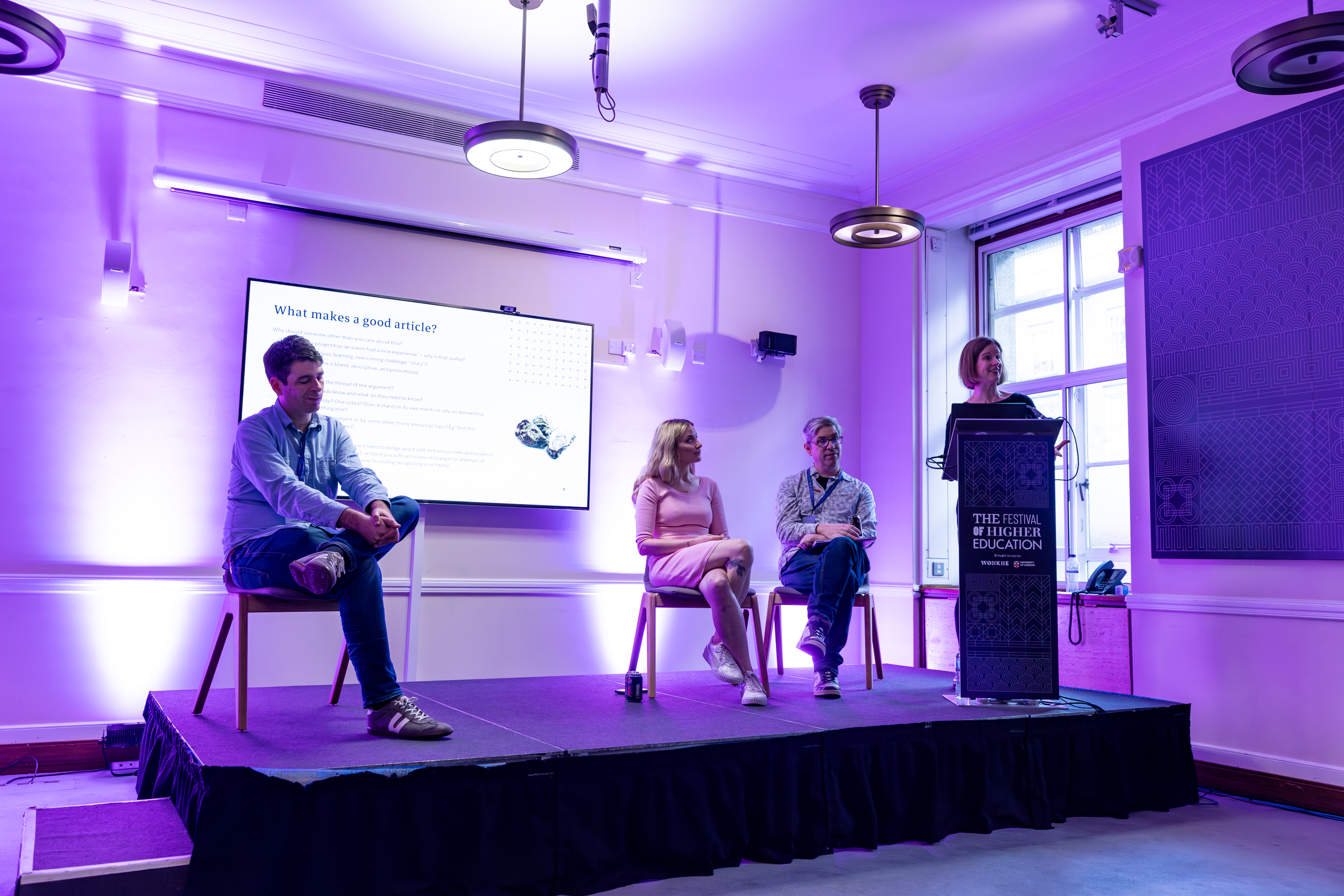 Panel discussion in Woburn Suite, University of London, with purple lighting and speakers.