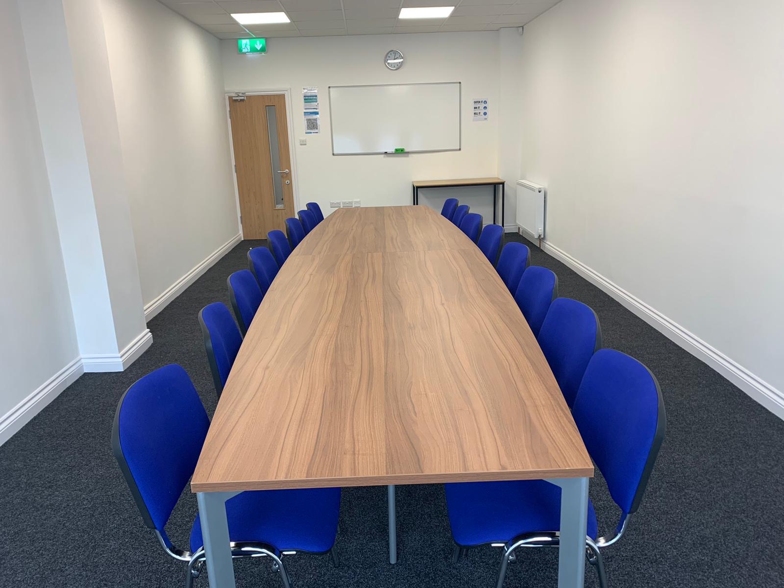 Meeting Room 2 at Bridge School: wooden table, blue chairs, ideal for workshops and meetings.