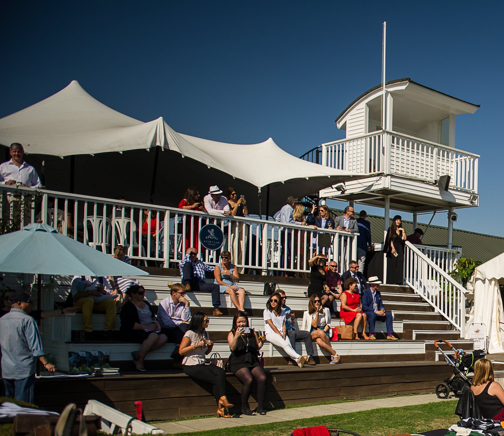 Rooftop terrace at Ham Polo Club, vibrant outdoor event with tiered seating for networking.