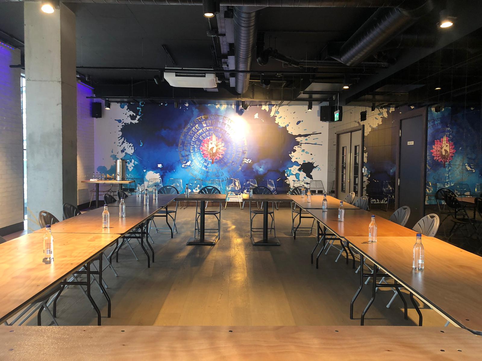 Versatile OmStudio meeting space with U-shaped tables, ideal for workshops and meetings.