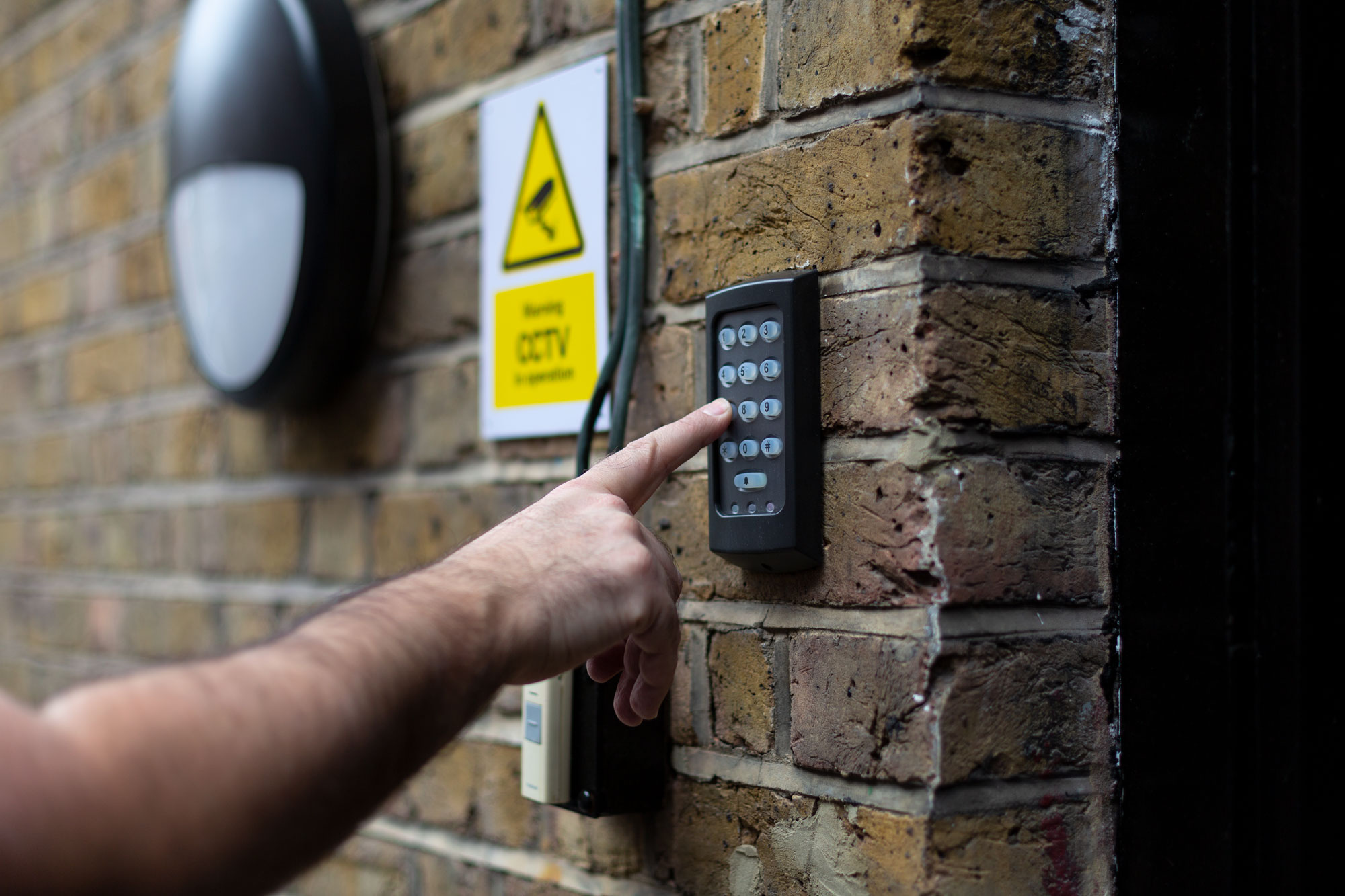 Person using keypad entry at KOZMIK WORK SPACE for secure event access.