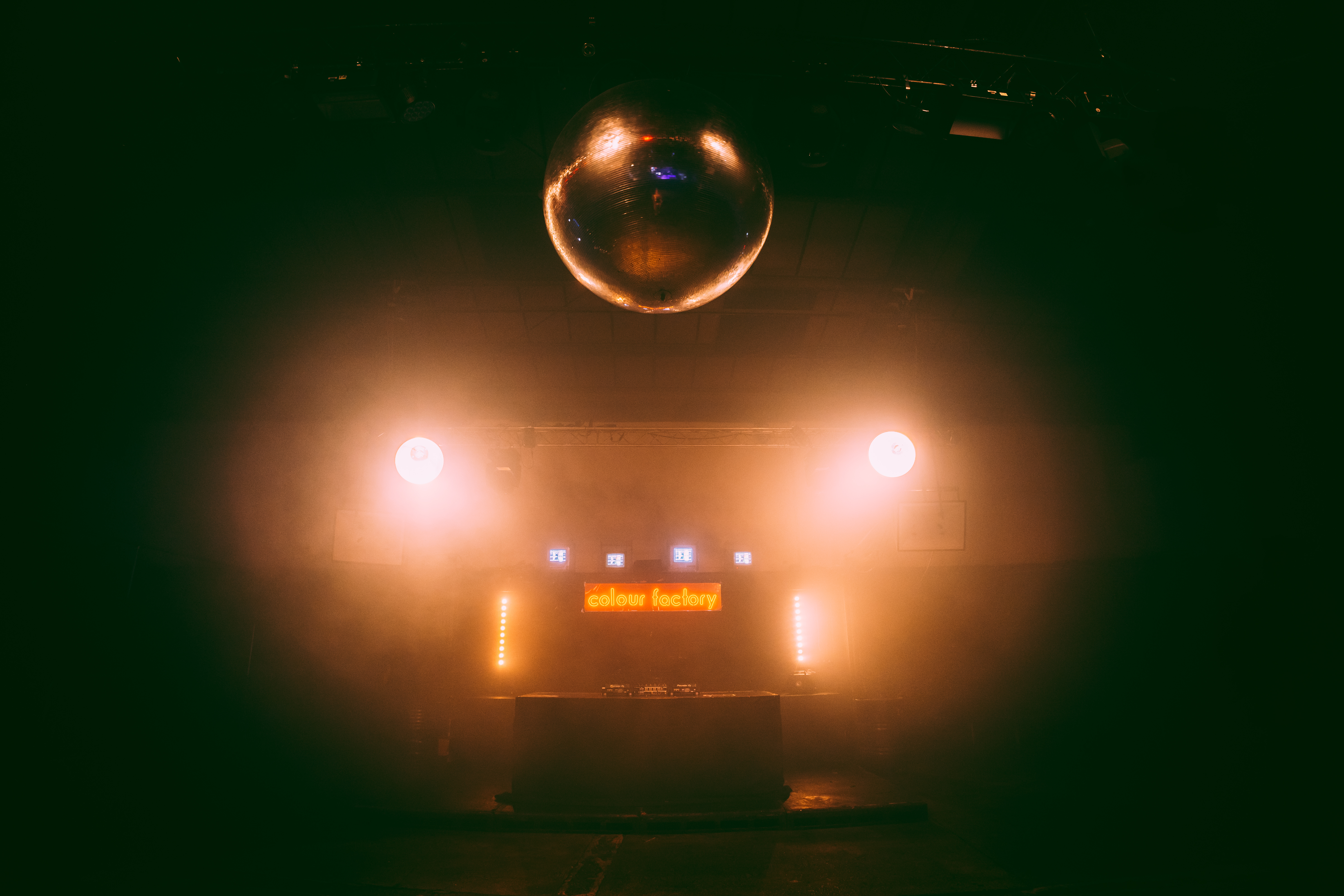 Dynamic event space with DJ booth, disco ball, ideal for nightlife and parties.