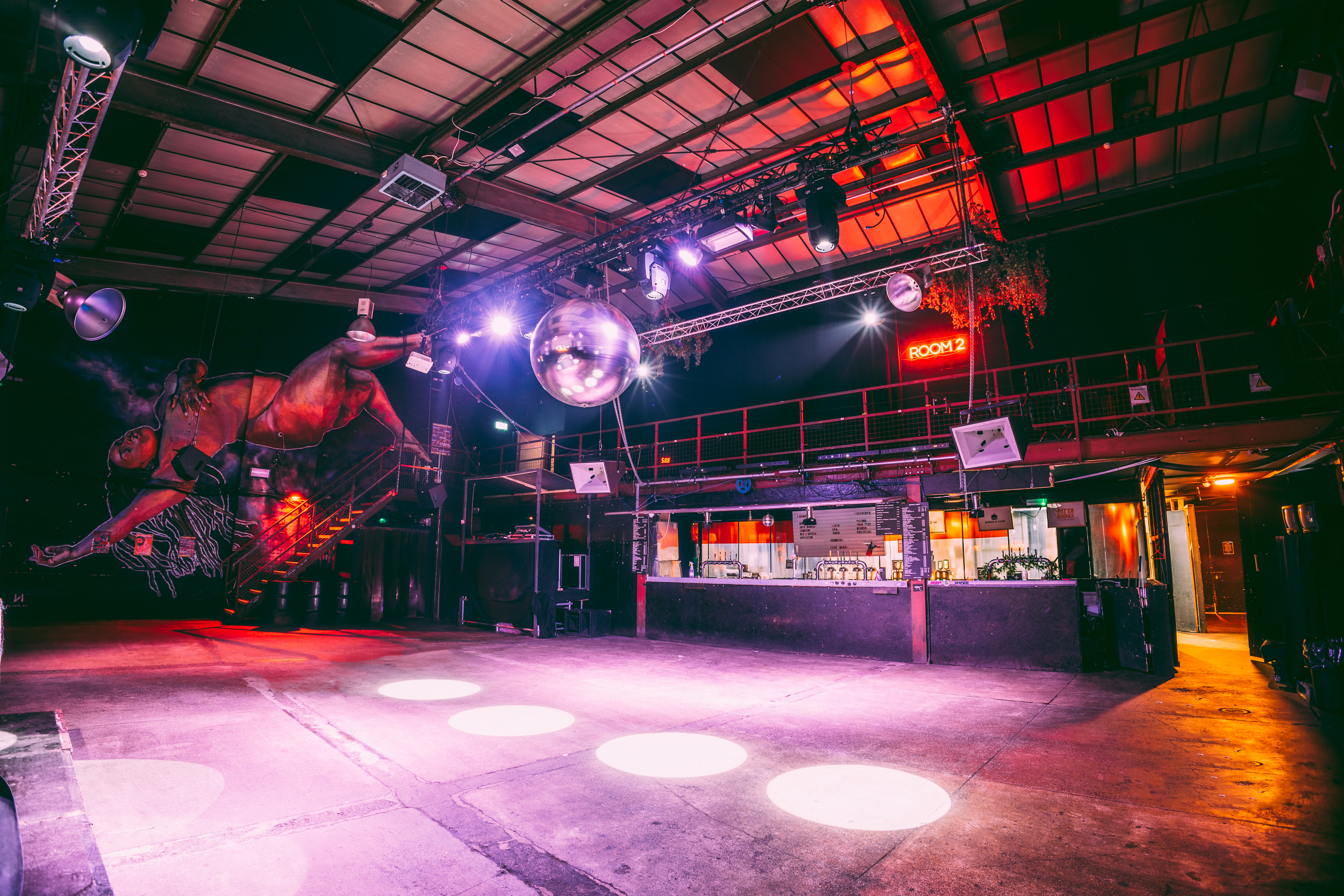 Versatile industrial event space with dance floor, ideal for concerts and parties.