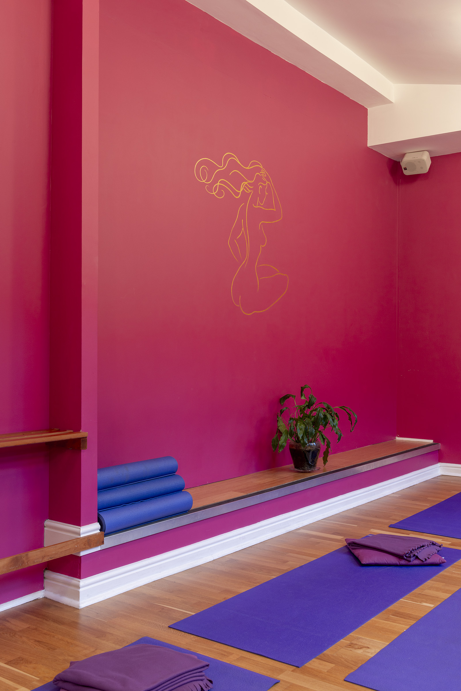 Vibrant pink wall with minimalist yoga art at Parvati Studio, perfect for wellness retreats.
