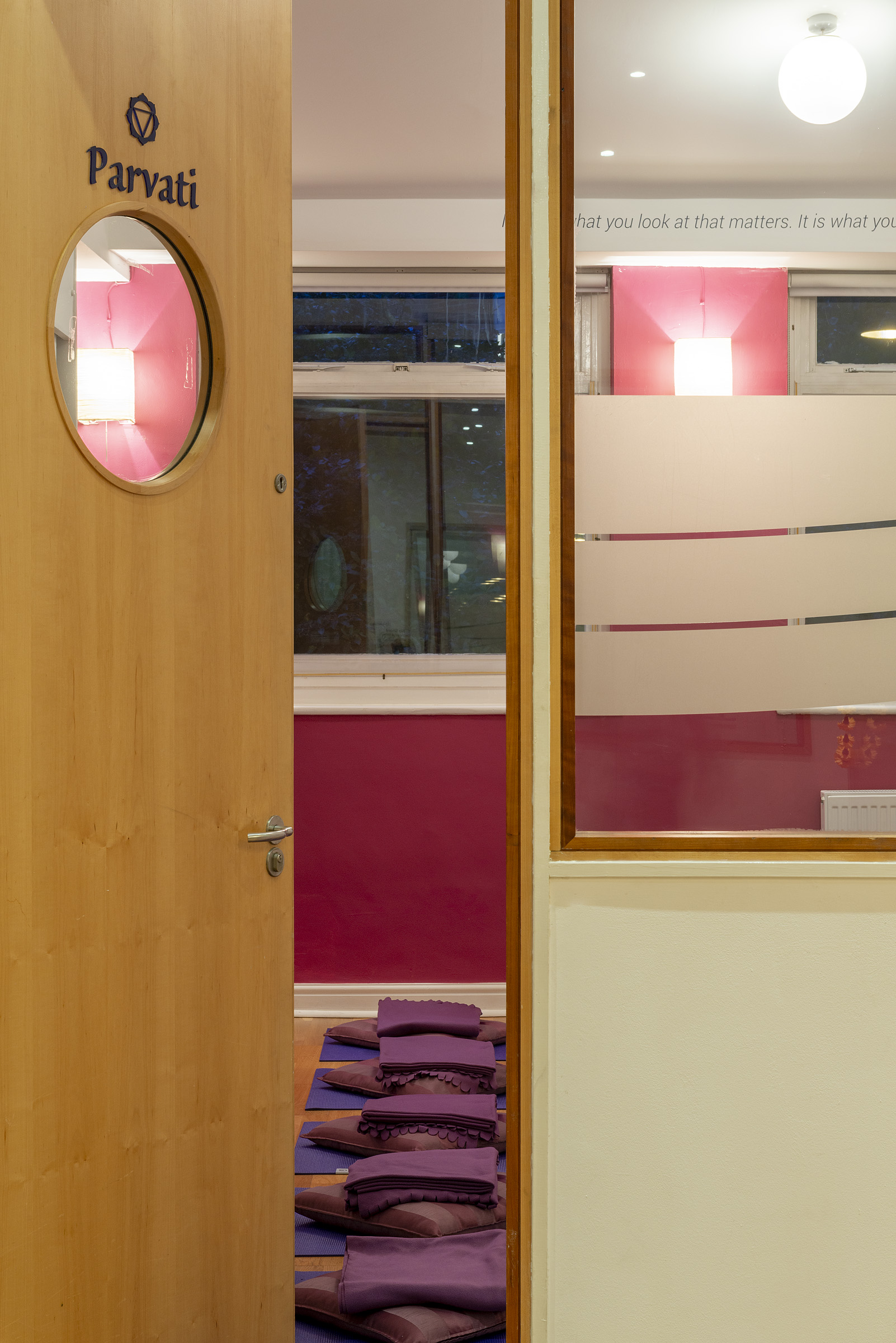 Modern meeting space entrance at Tara Yoga Centre with sleek wooden door and pink wall.