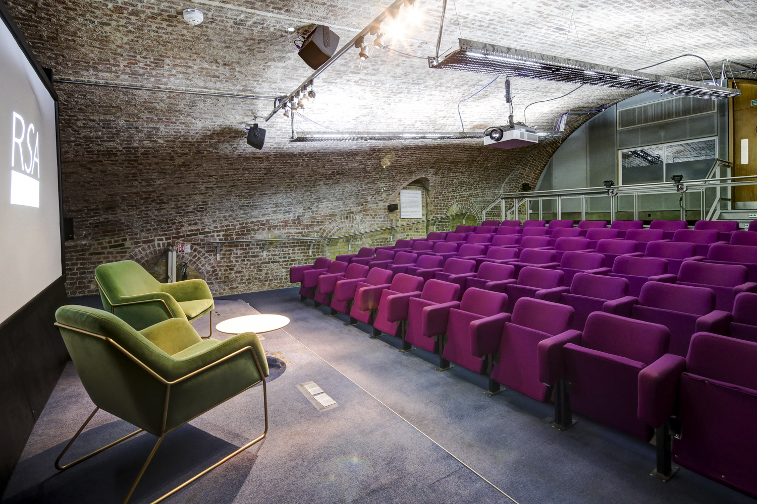 Filming in modern RSA House auditorium with vibrant purple seating for events.