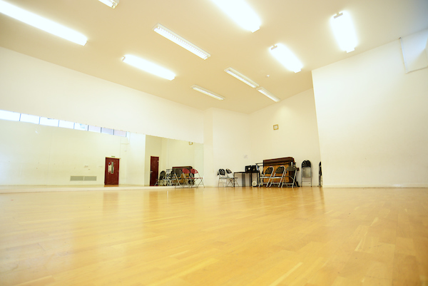 Spacious dance studio with polished wooden floor, ideal for workshops and fitness classes.