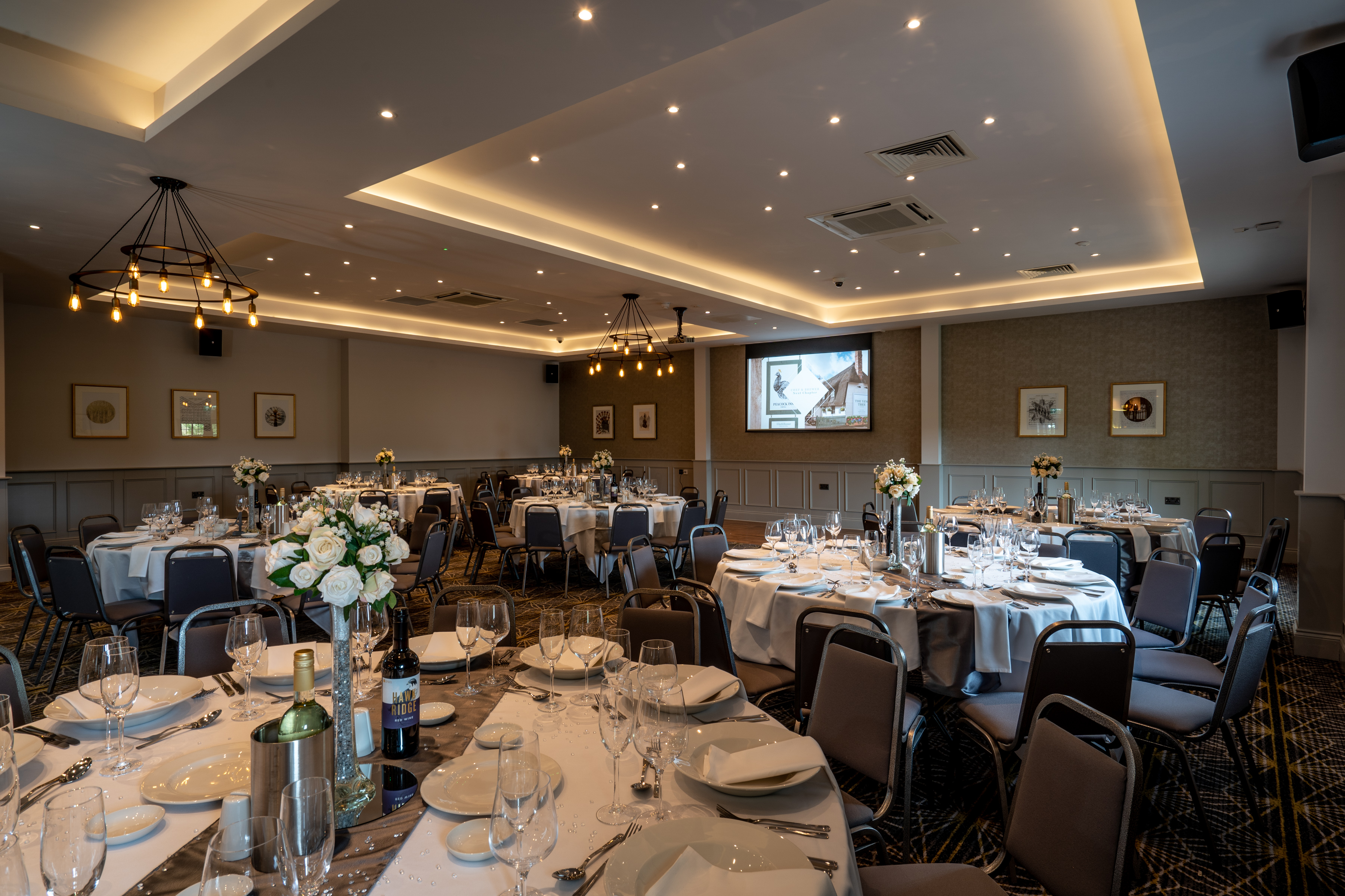 Elegant event space at The Barn, featuring round tables and floral centerpieces for meetings.