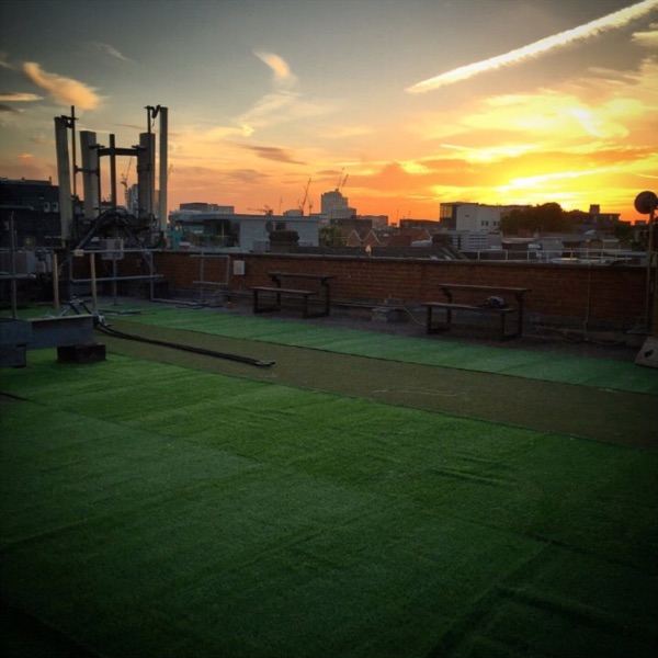 Rooftop gym venue in London with artificial turf, perfect for outdoor events at sunset.