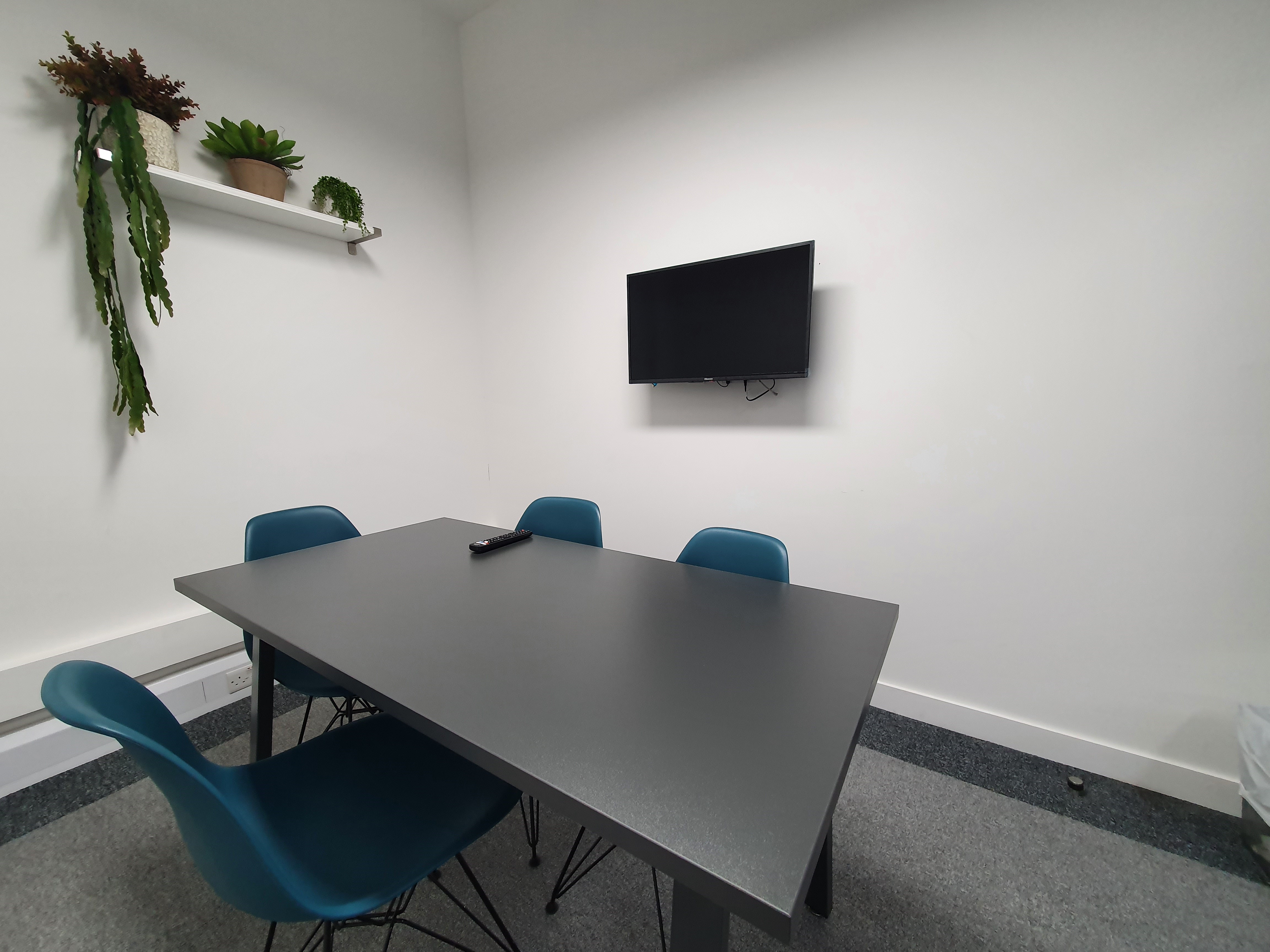 Modern Jimmy Green Meeting Room with teal chairs, ideal for presentations and brainstorming.
