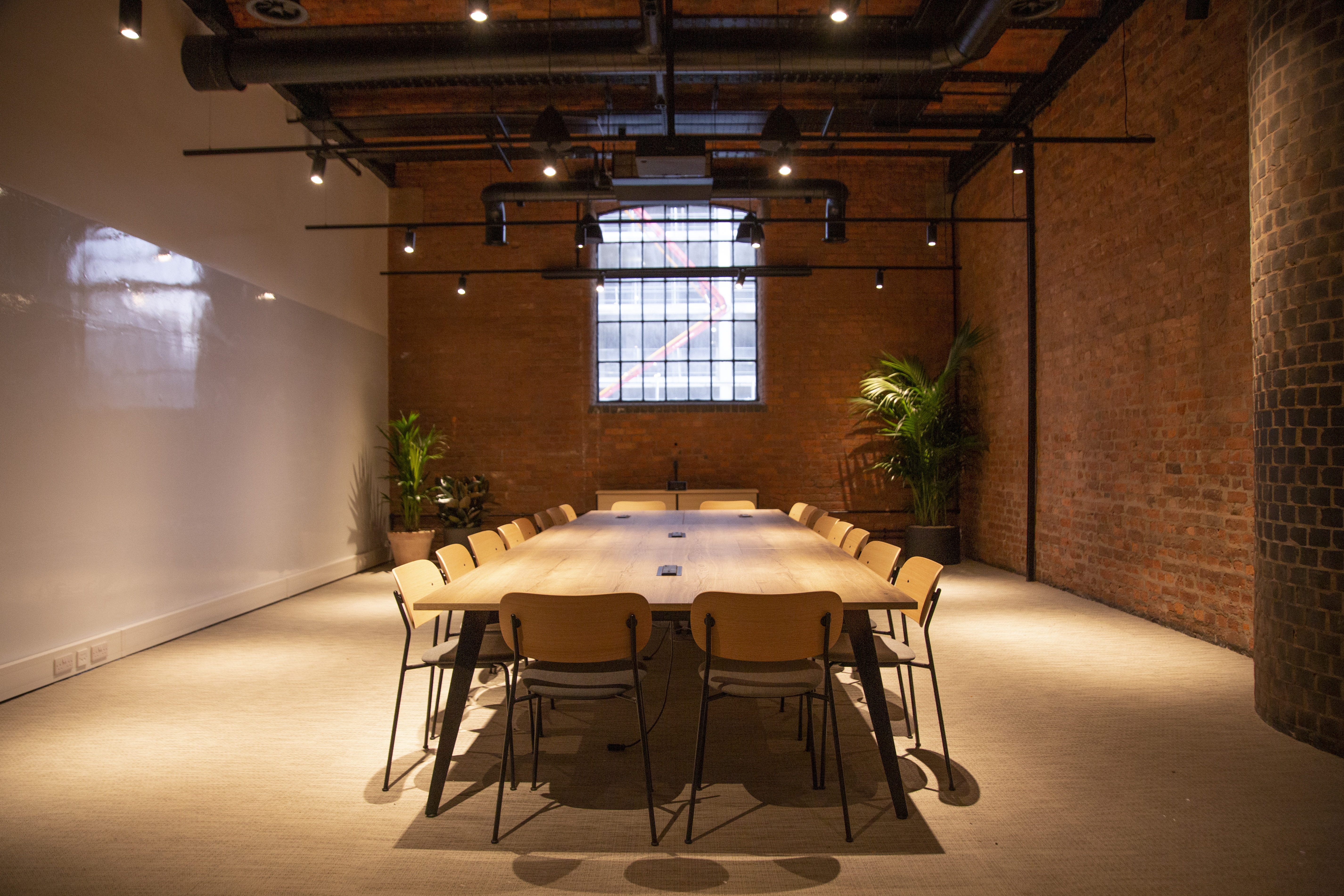 Modern meeting room with long table, exposed brick walls for workshops and strategic sessions.