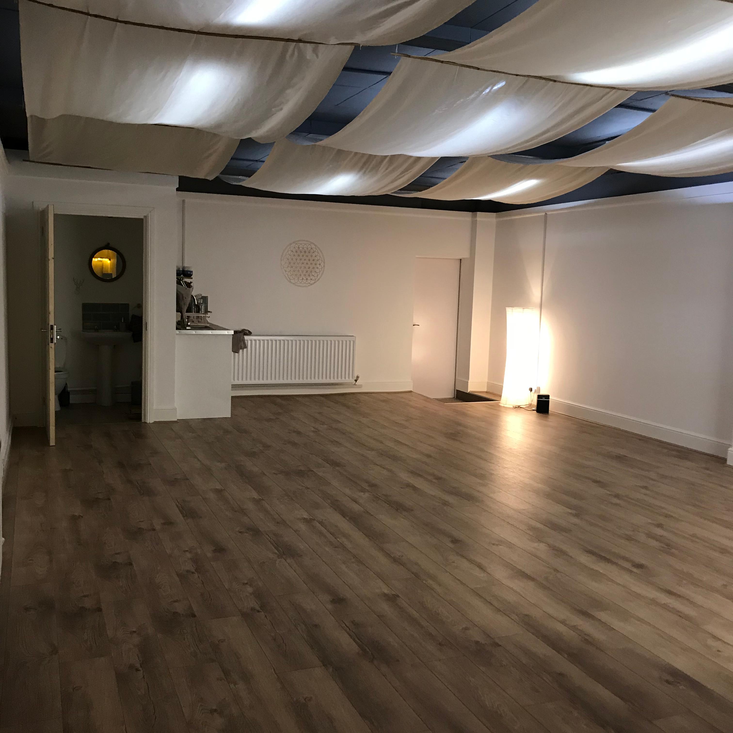 Versatile yoga studio with wooden flooring, ideal for workshops and gatherings.