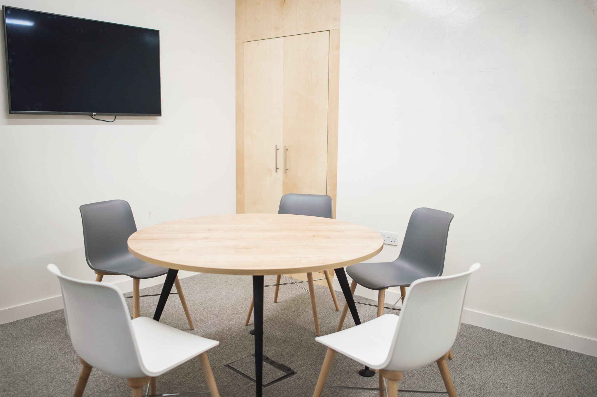 Modern meeting space with round wooden table, ideal for collaborative discussions and presentations.