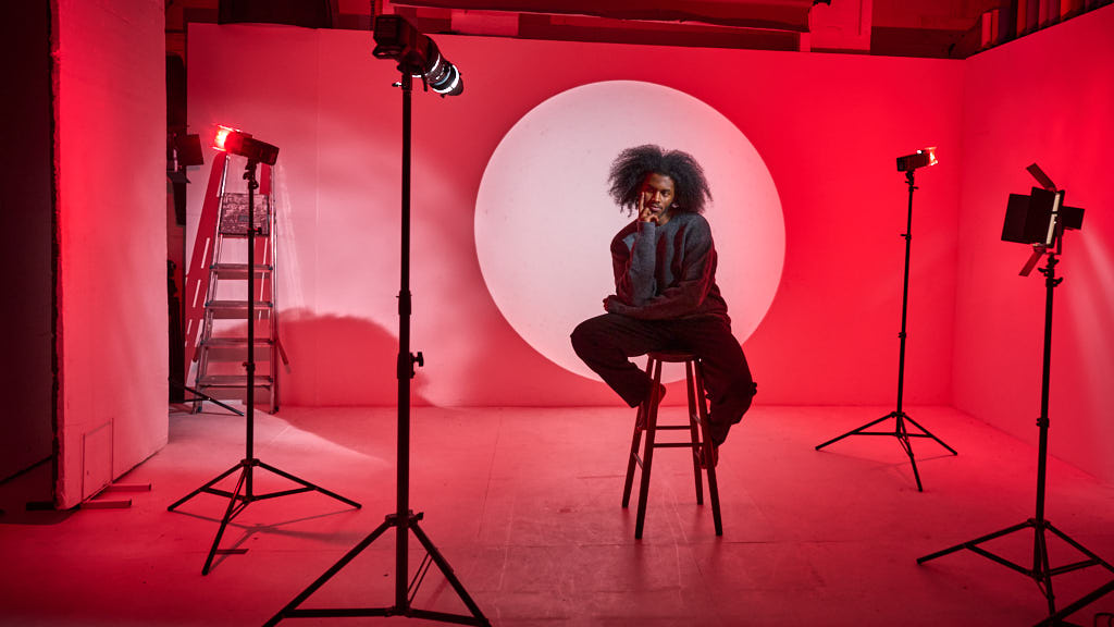 Creative photoshoot setup with dramatic red lighting and minimalist backdrop.