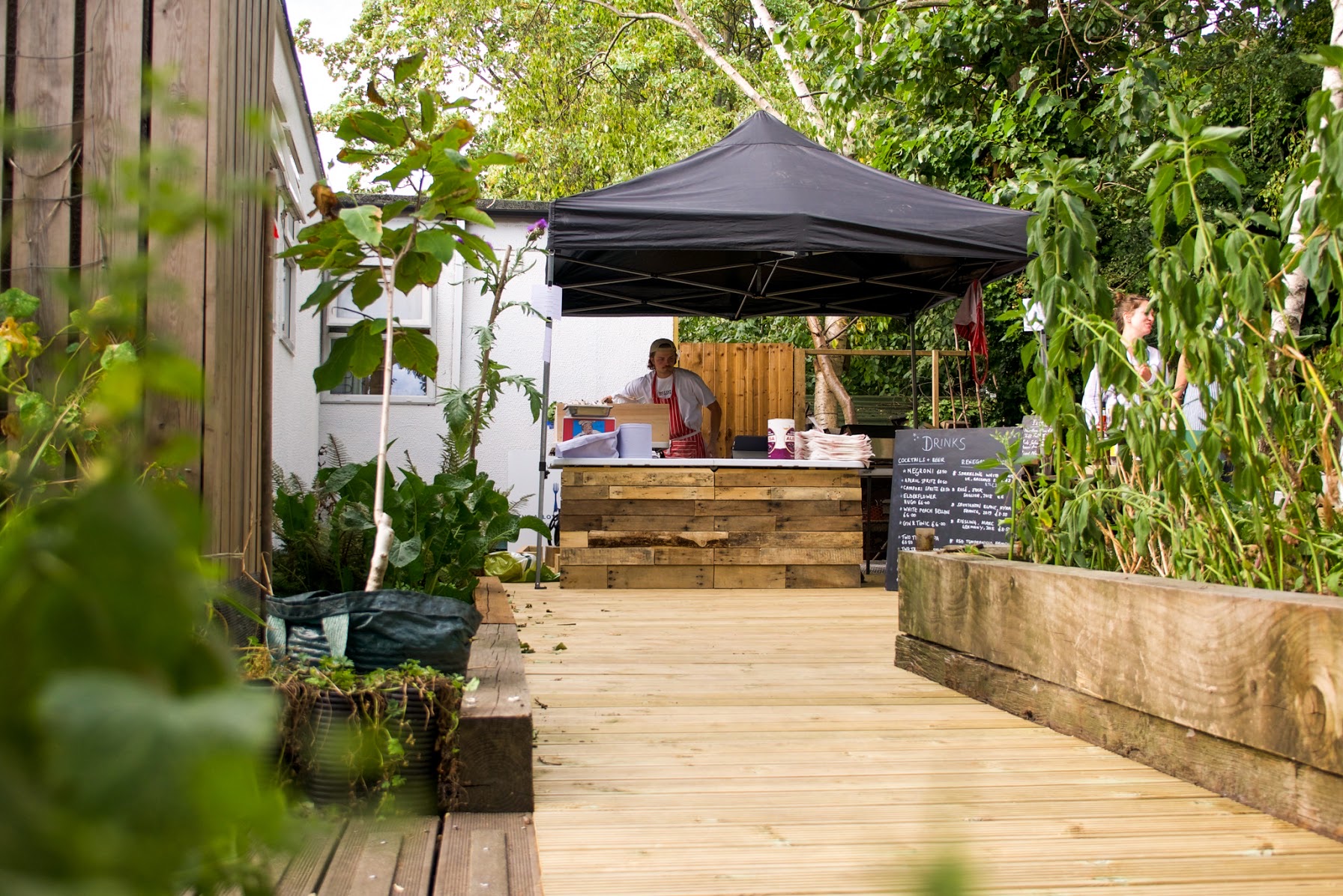 Charming outdoor event space with wooden deck and black canopy for gatherings and workshops.