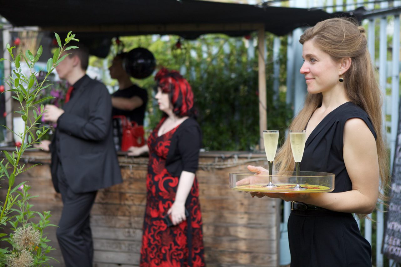 Elegant outdoor event at Brunel Museum with stylish guests and rustic bar.
