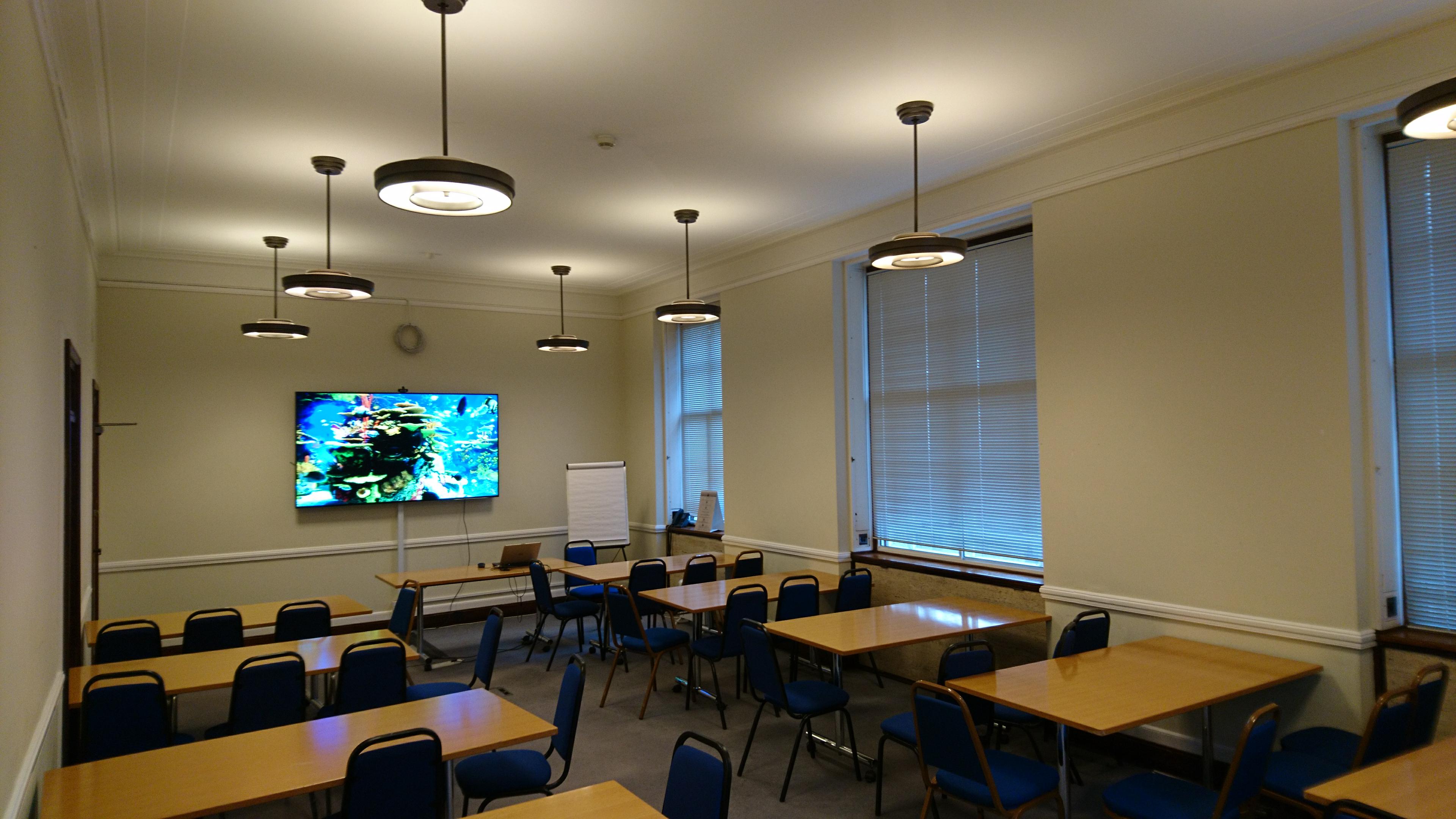 Well-lit Senate House meeting room with large screen for collaborative events.