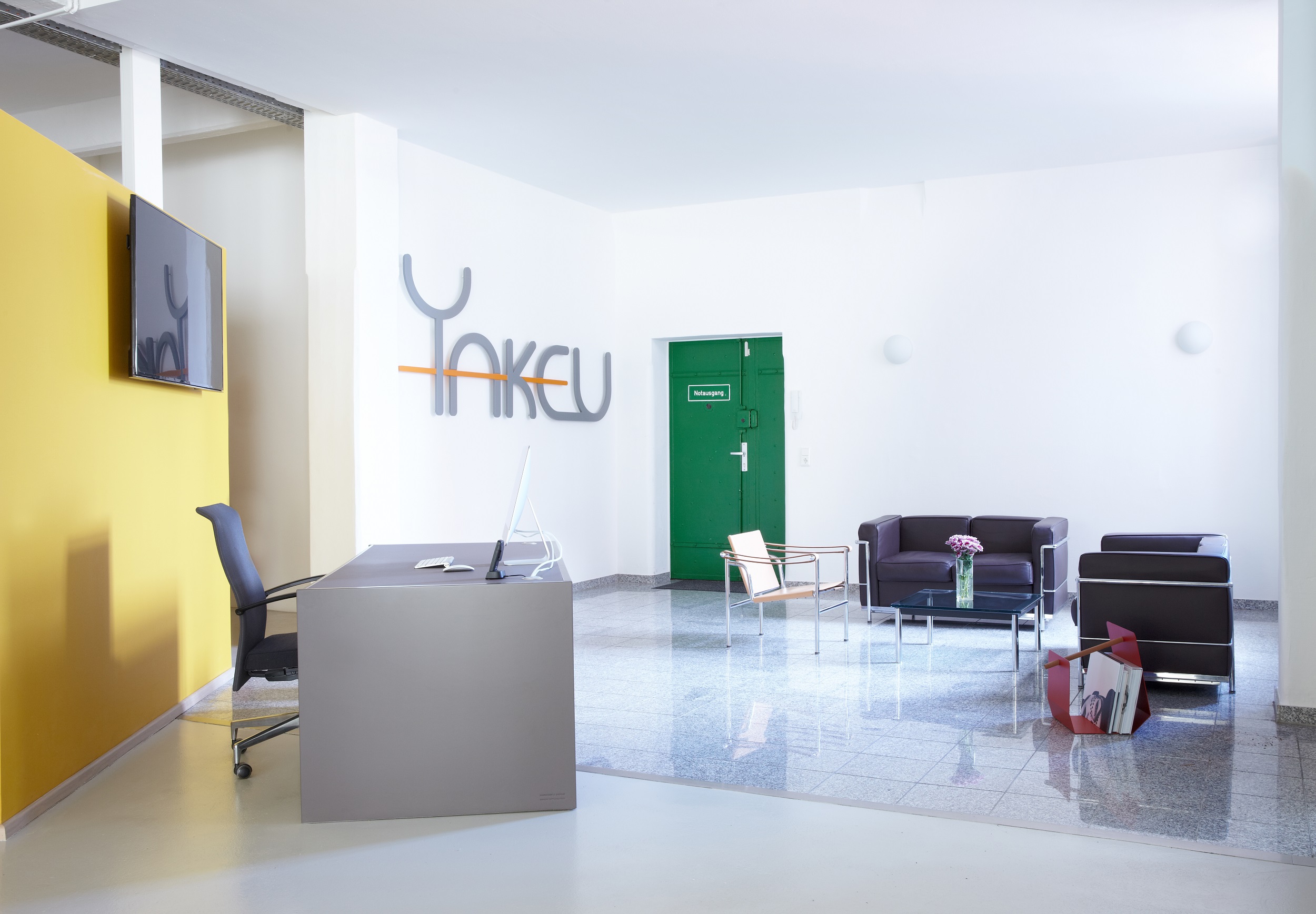 Modern reception area at Yakeu Studio with vibrant yellow wall, perfect for events.