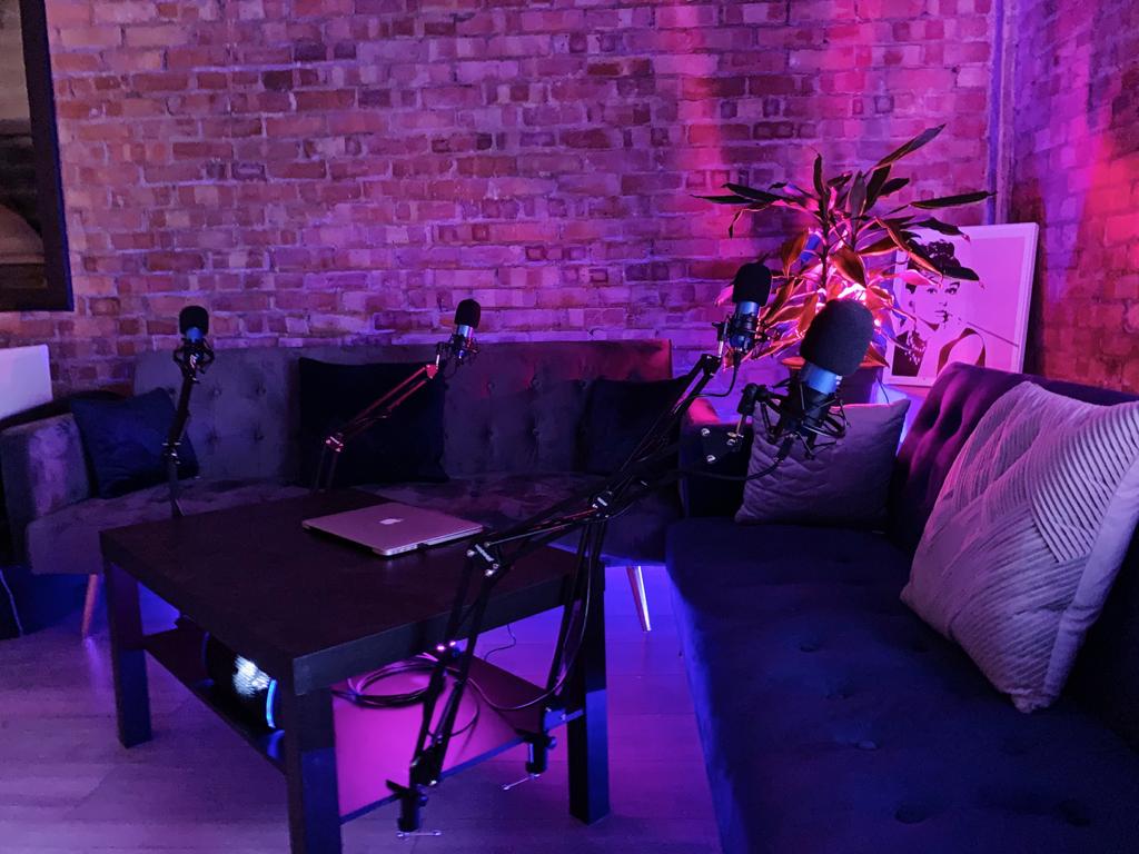 Cozy podcasting setup with microphones and purple lighting for creative events.