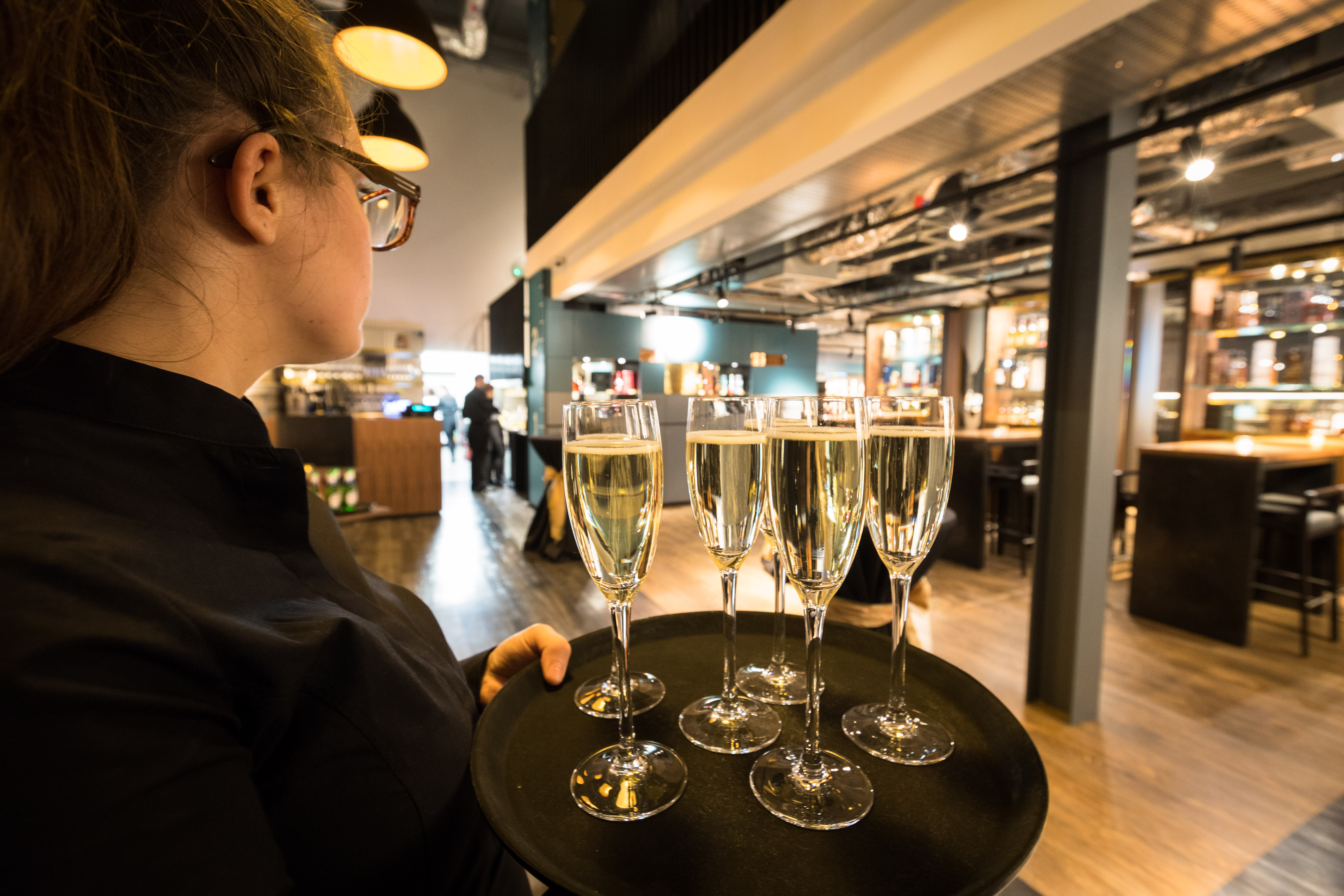 Professional server with champagne flutes in stylish Clydeside Distillery venue for events.