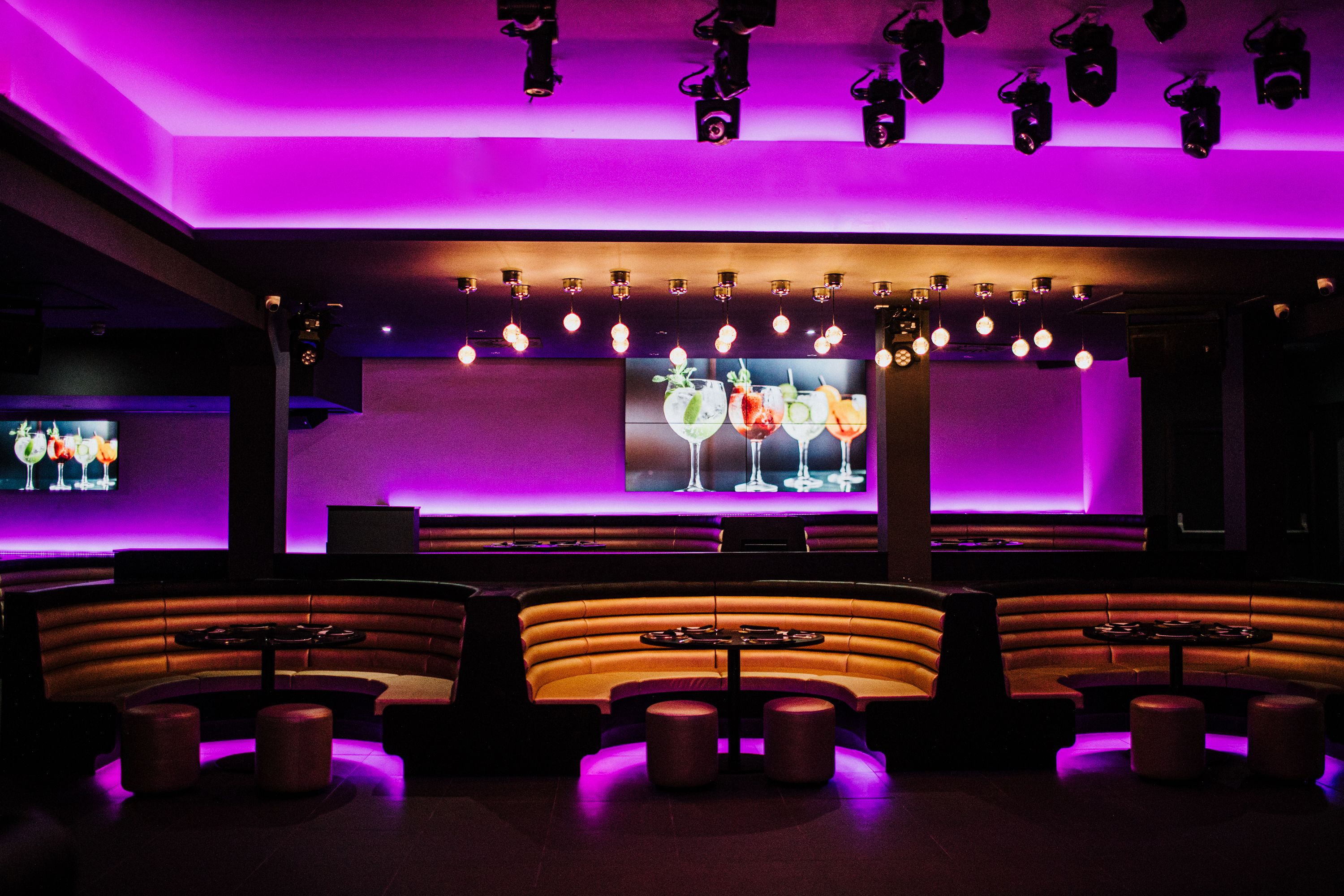 Modern event space with curved seating and purple lighting for themed gatherings.