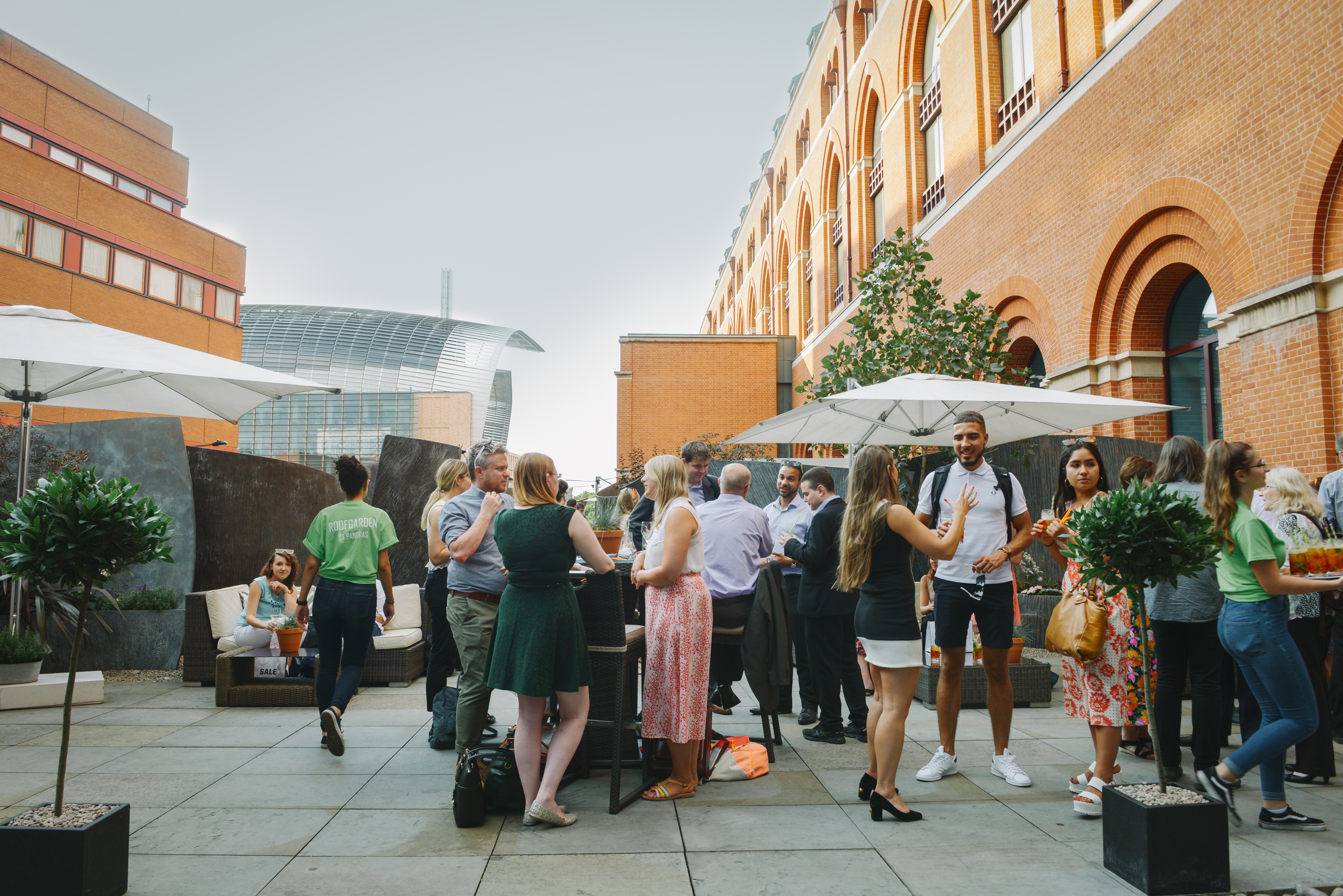 Vibrant outdoor networking event at RoofGarden St. Pancras with umbrellas and greenery.