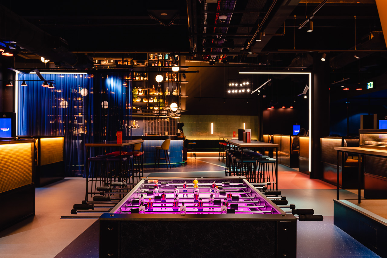 Modern event space at TOCA Social with vibrant bar and foosball table for gatherings.