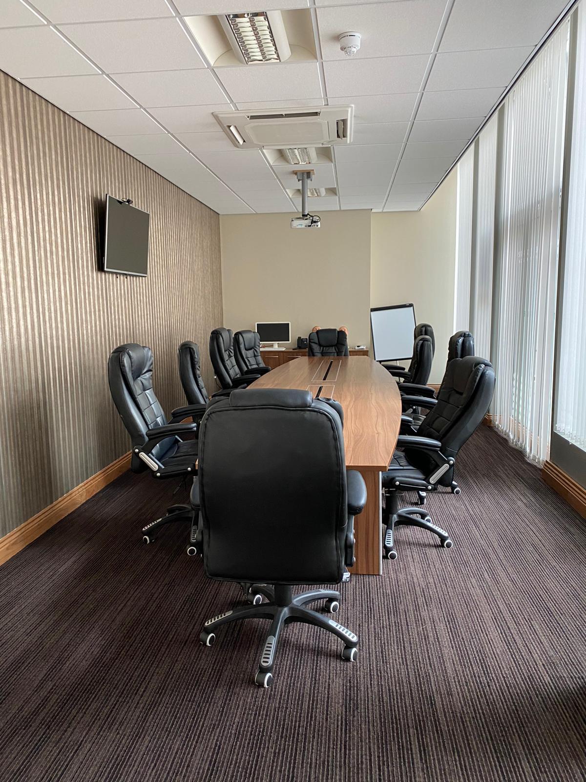 Conference room for hire in Pall Mall Medical, featuring a long wooden table and ergonomic chairs.