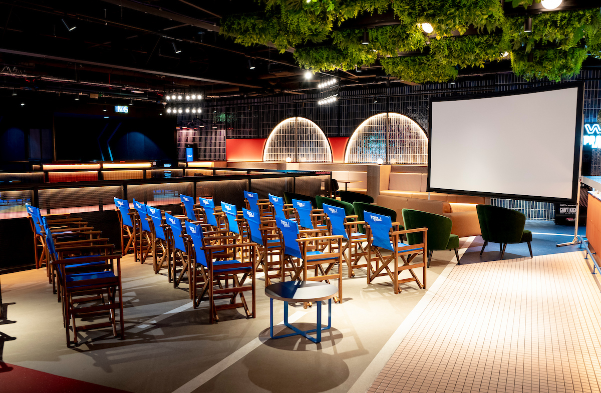 Modern event space with director chairs and large screen for creative meetings.