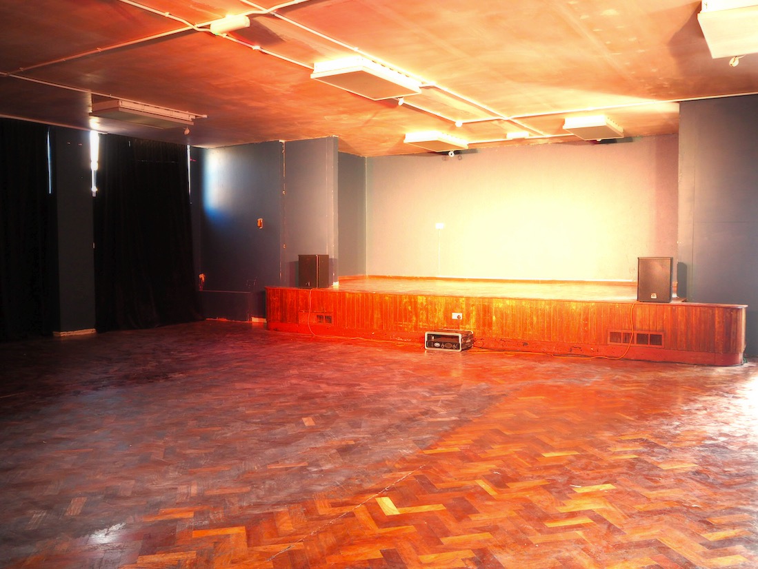 Versatile event space with wooden stage, ideal for presentations and performances.