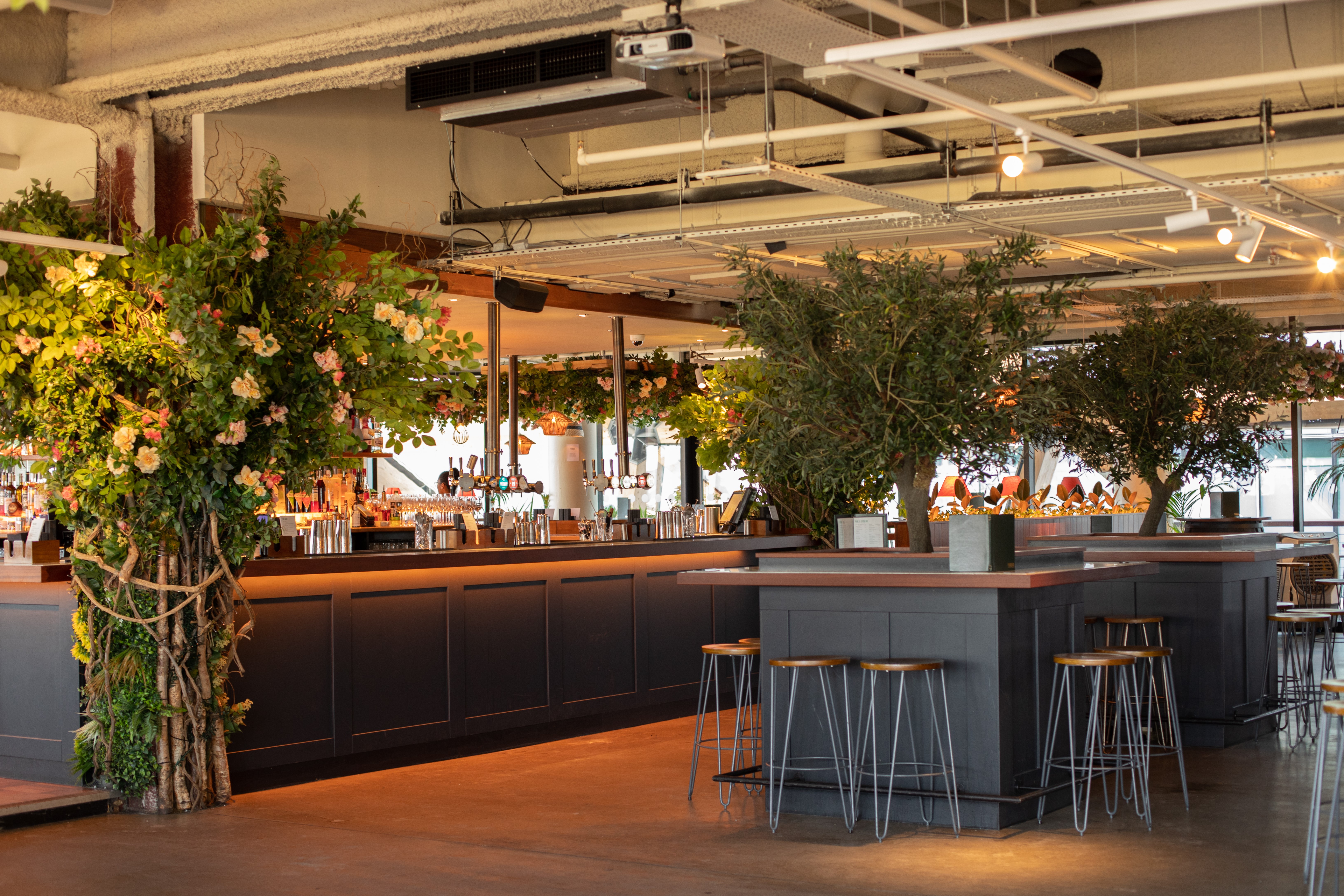 Stylish event space at Pergola on the Wharf with modern bar and lush greenery.